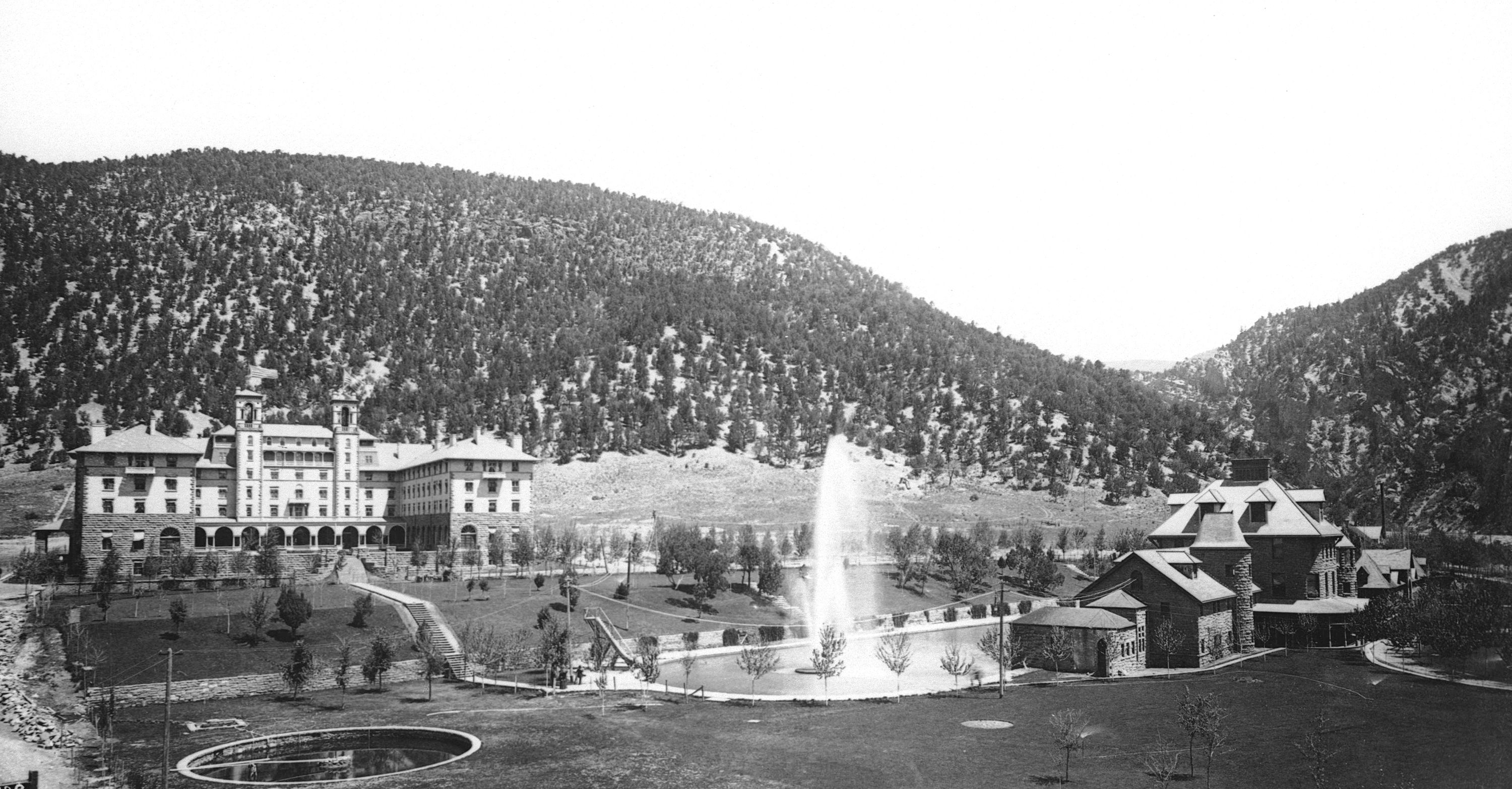 a building with a fountain in front of a hill
