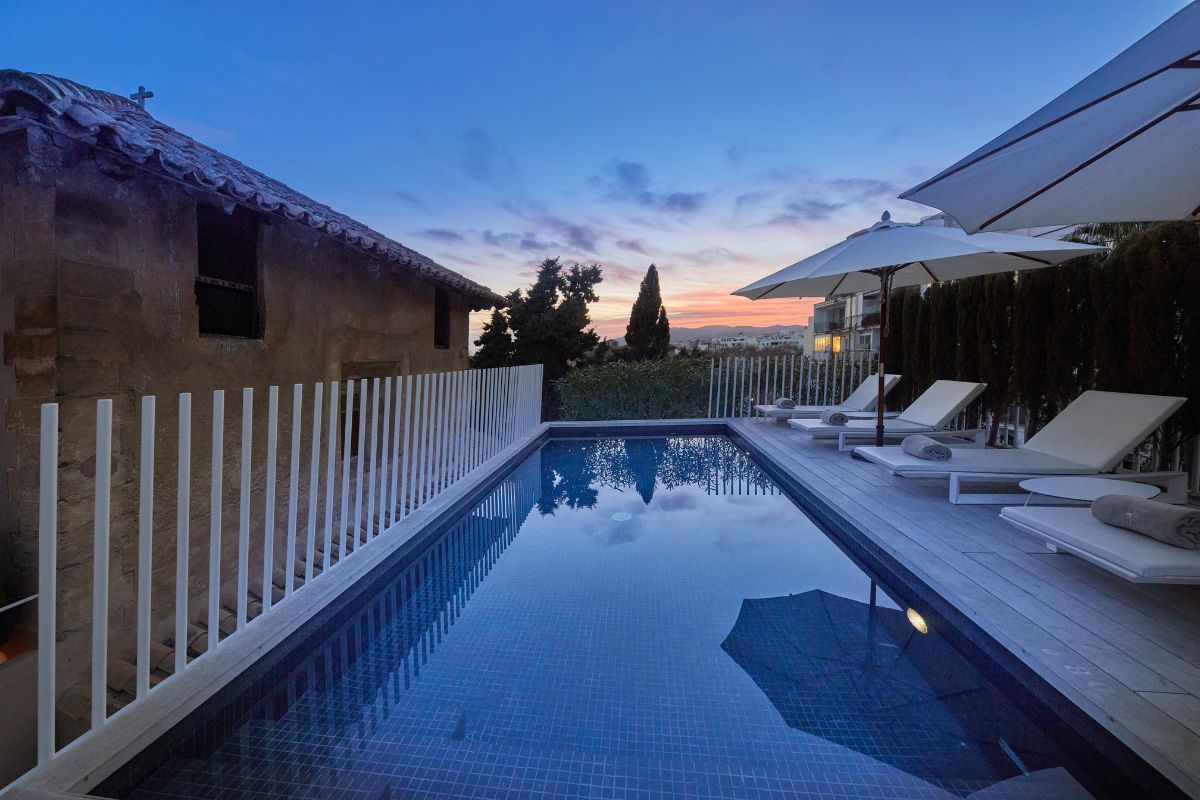 a pool with chairs and umbrellas by a house
