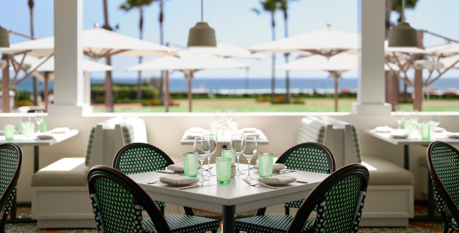 a table with green glasses and white chairs