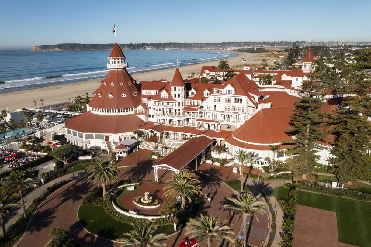 a large building with a red roof and a beach in the background