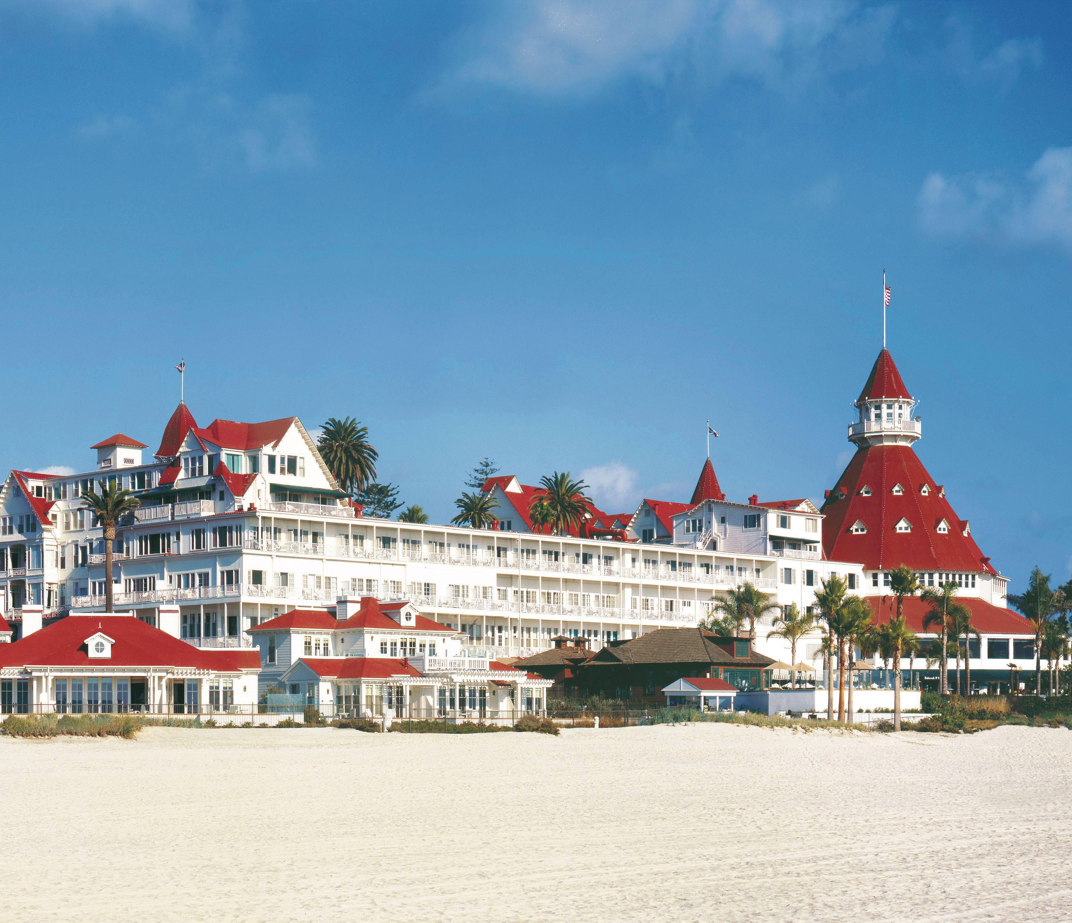 a large white building with red roofs with Hotel del Coronado in the background