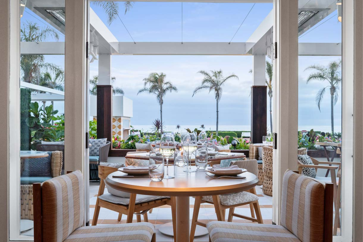 a table set up for dinner with chairs and a view of the ocean