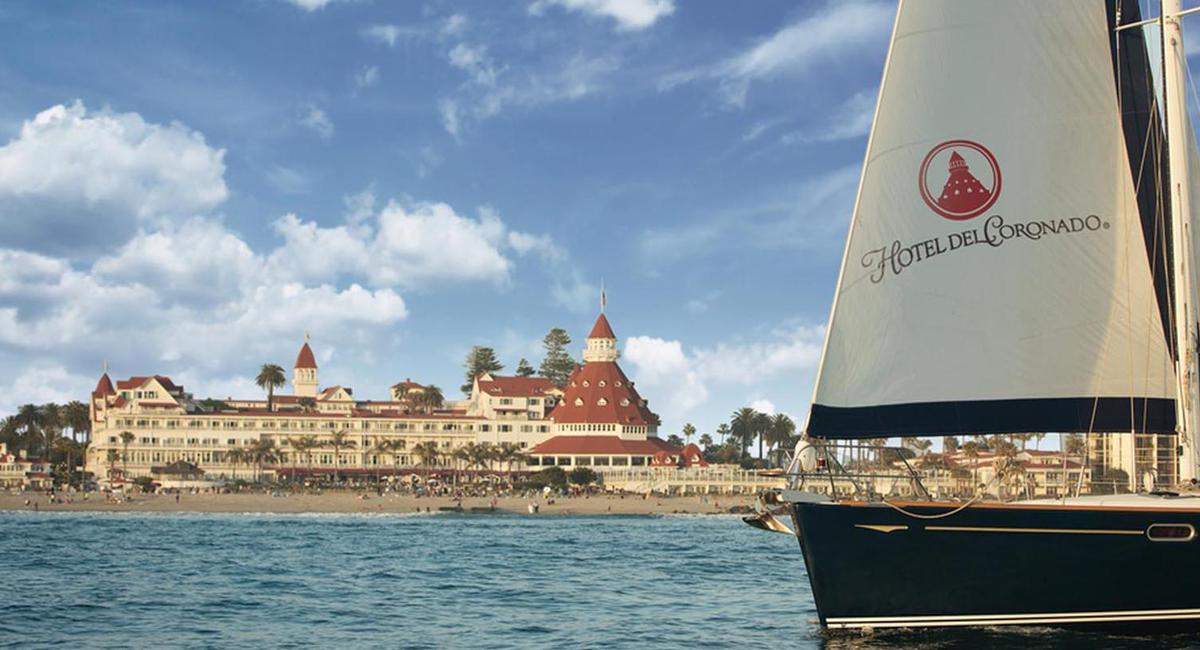 a sailboat in the water with a large building in the background