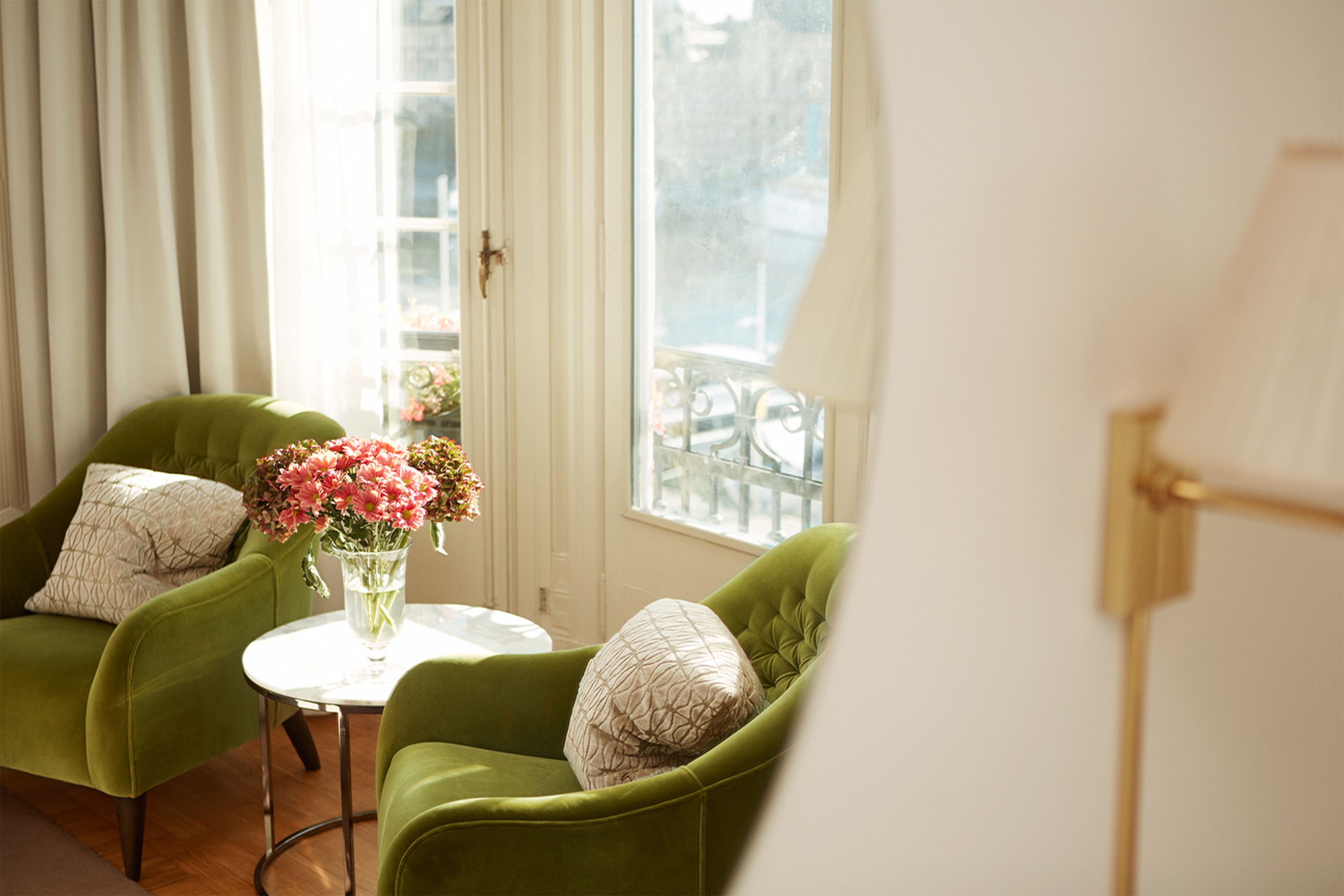 a room with green chairs and a vase of flowers