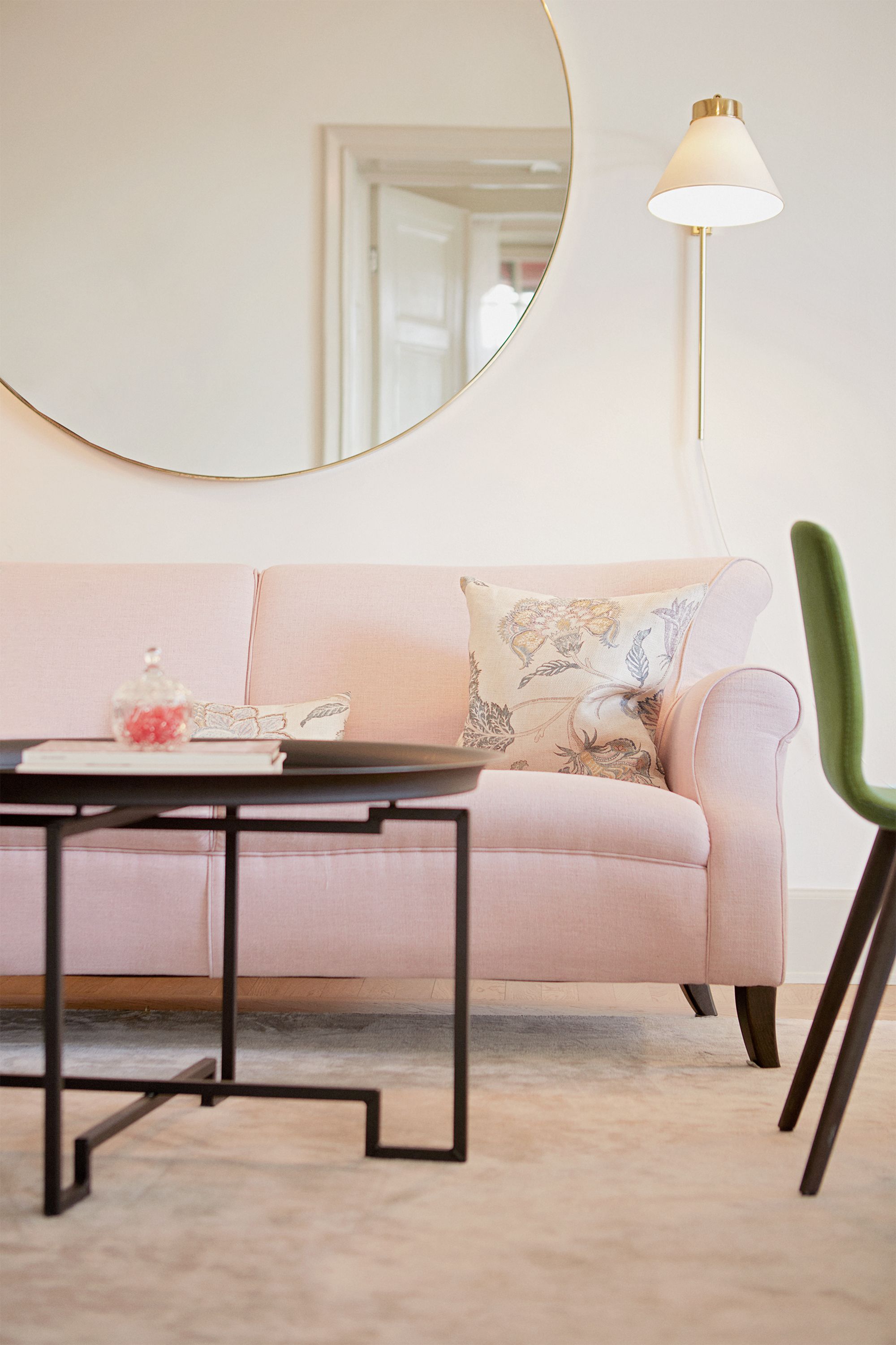 a pink couch with a round mirror on the wall