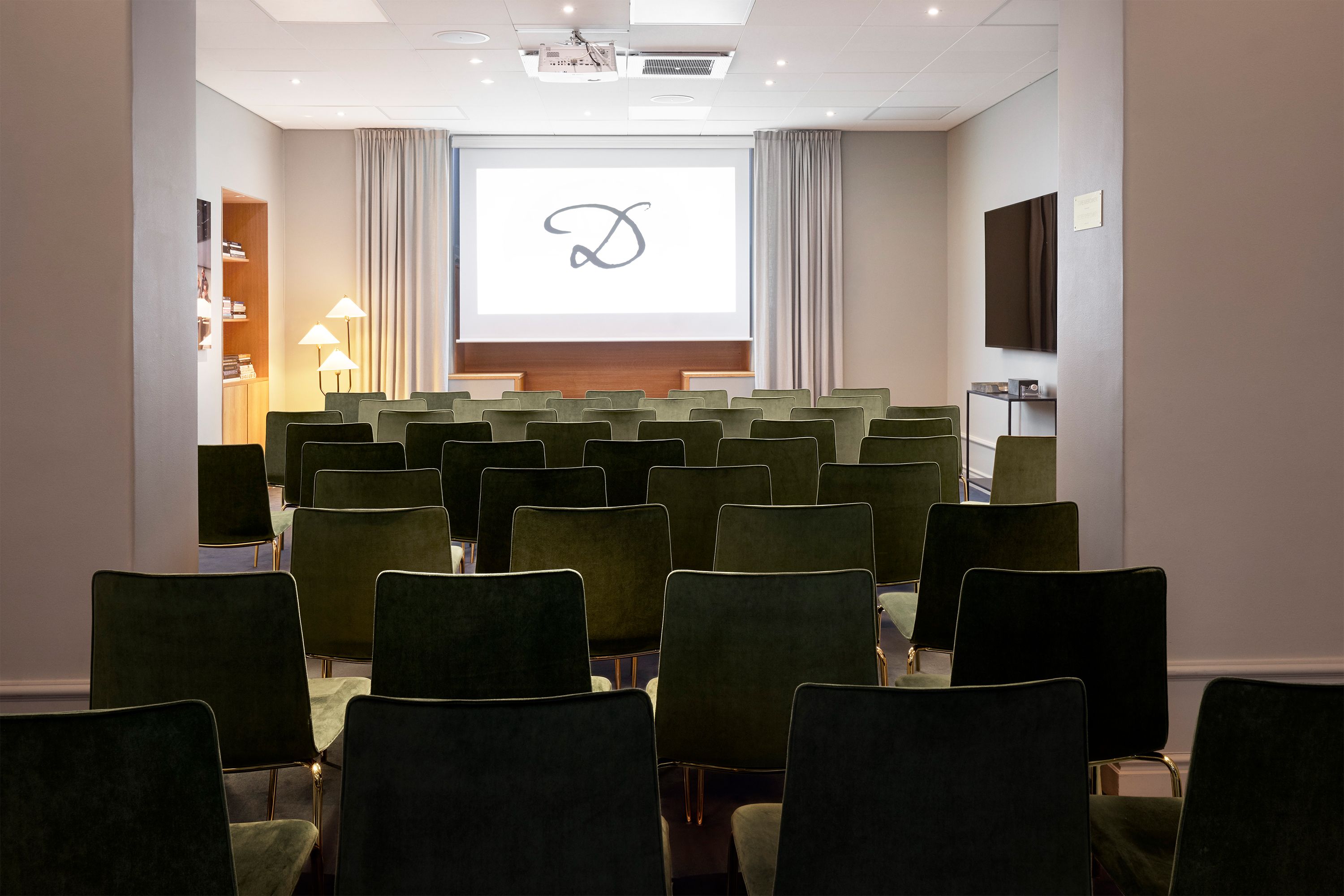 a room with green chairs and a projector screen