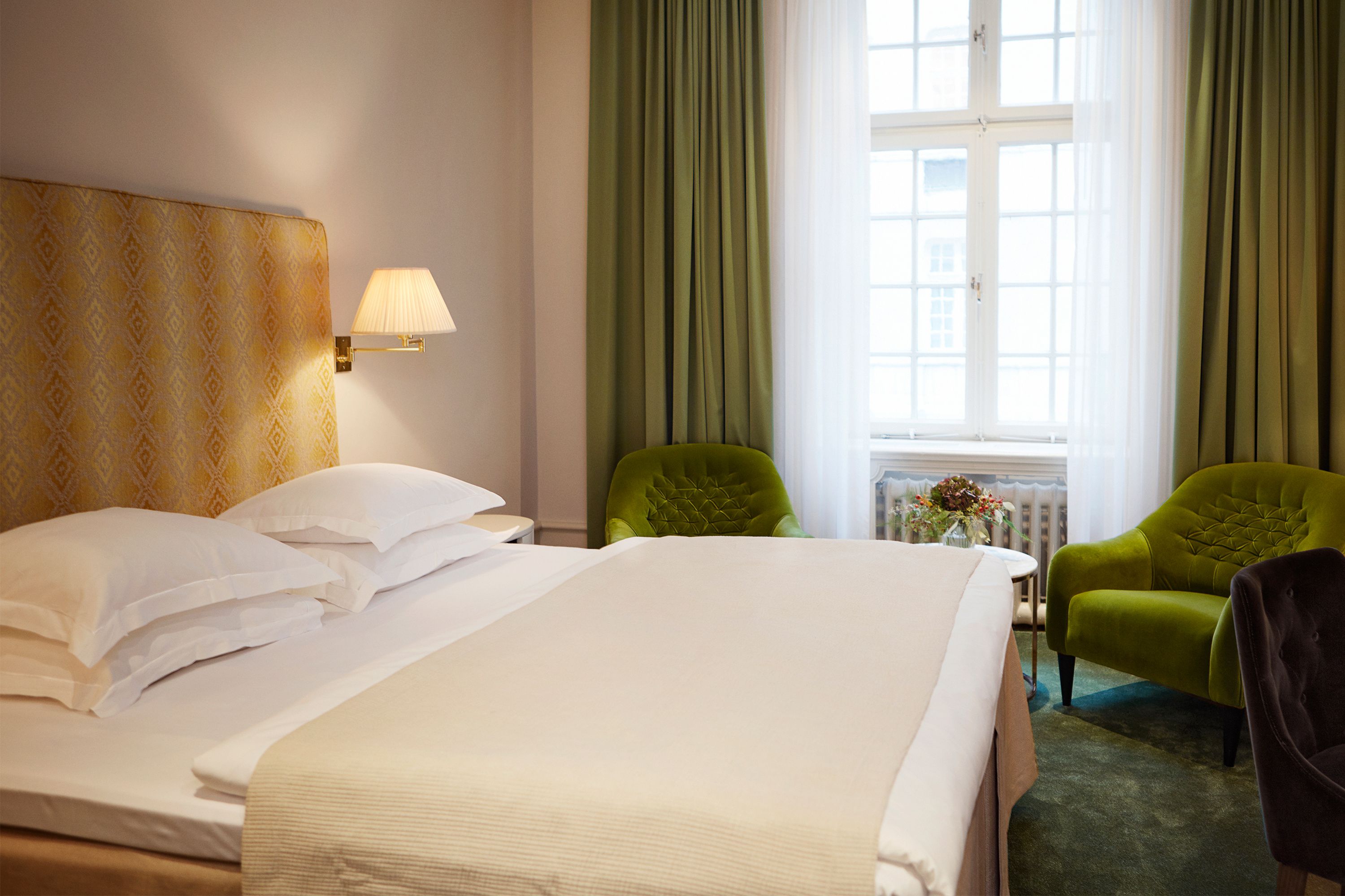 a room with a bed and green chairs