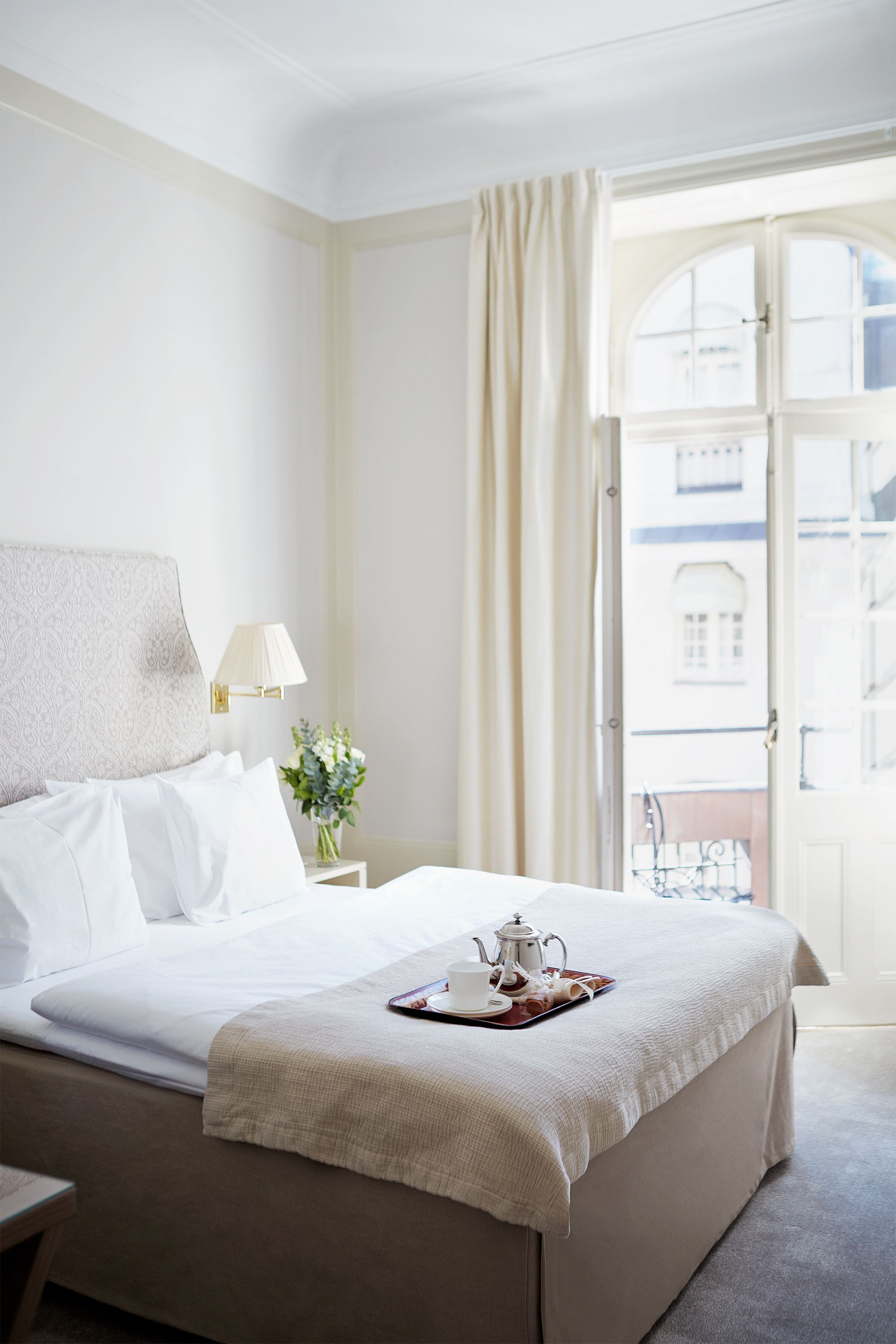 a bed with a tray of tea and a flower on it