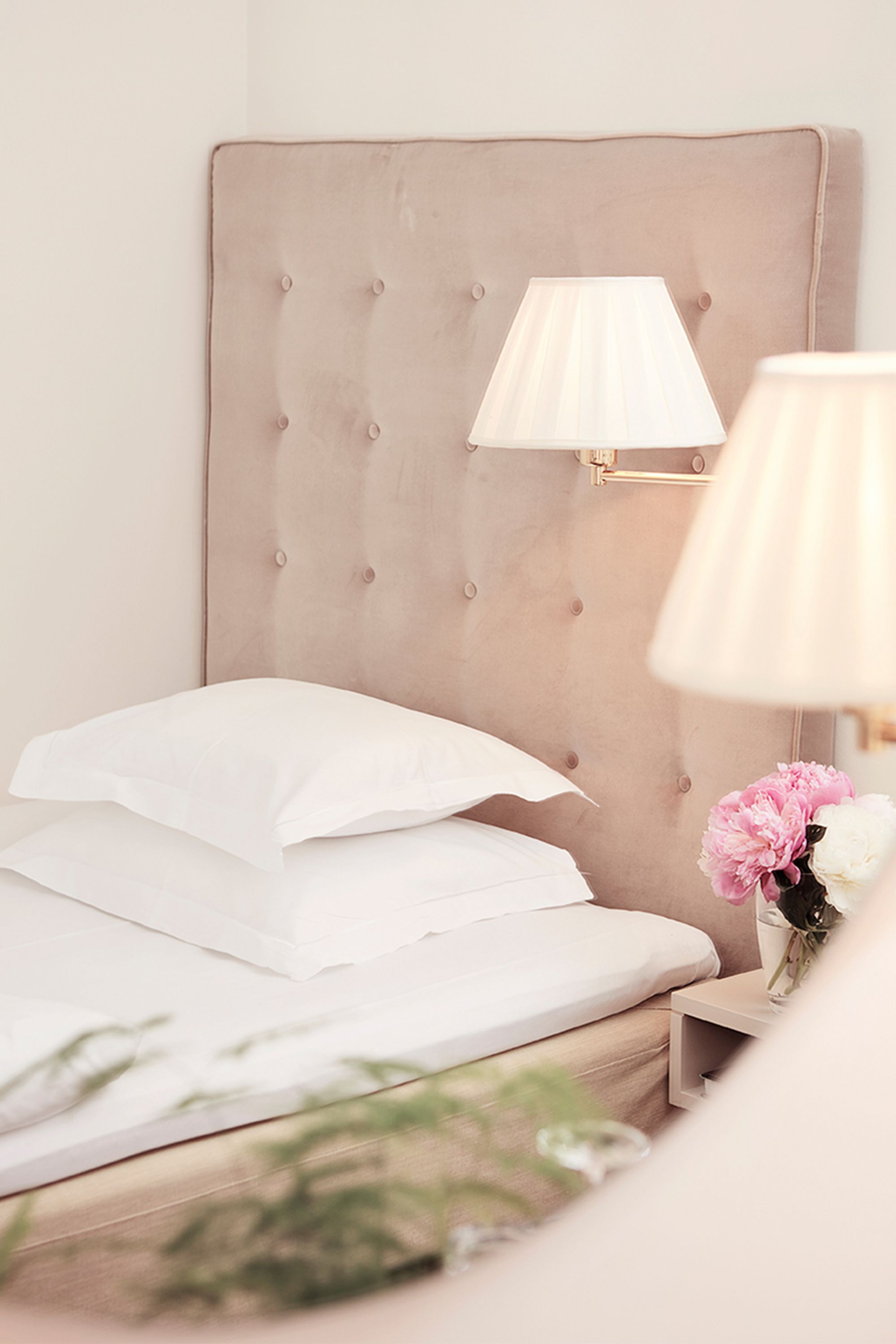 a bed with pillows and a vase of flowers