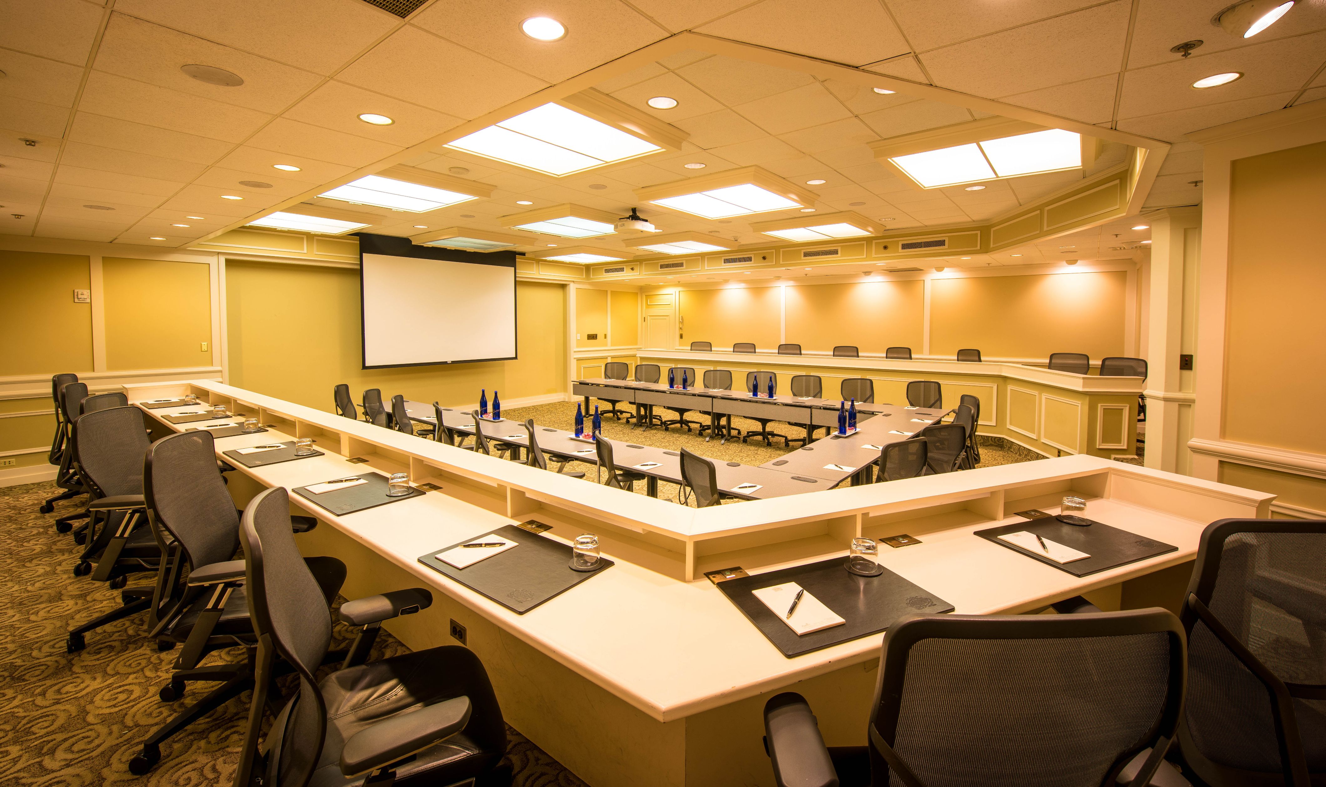 a room with a large screen and tables