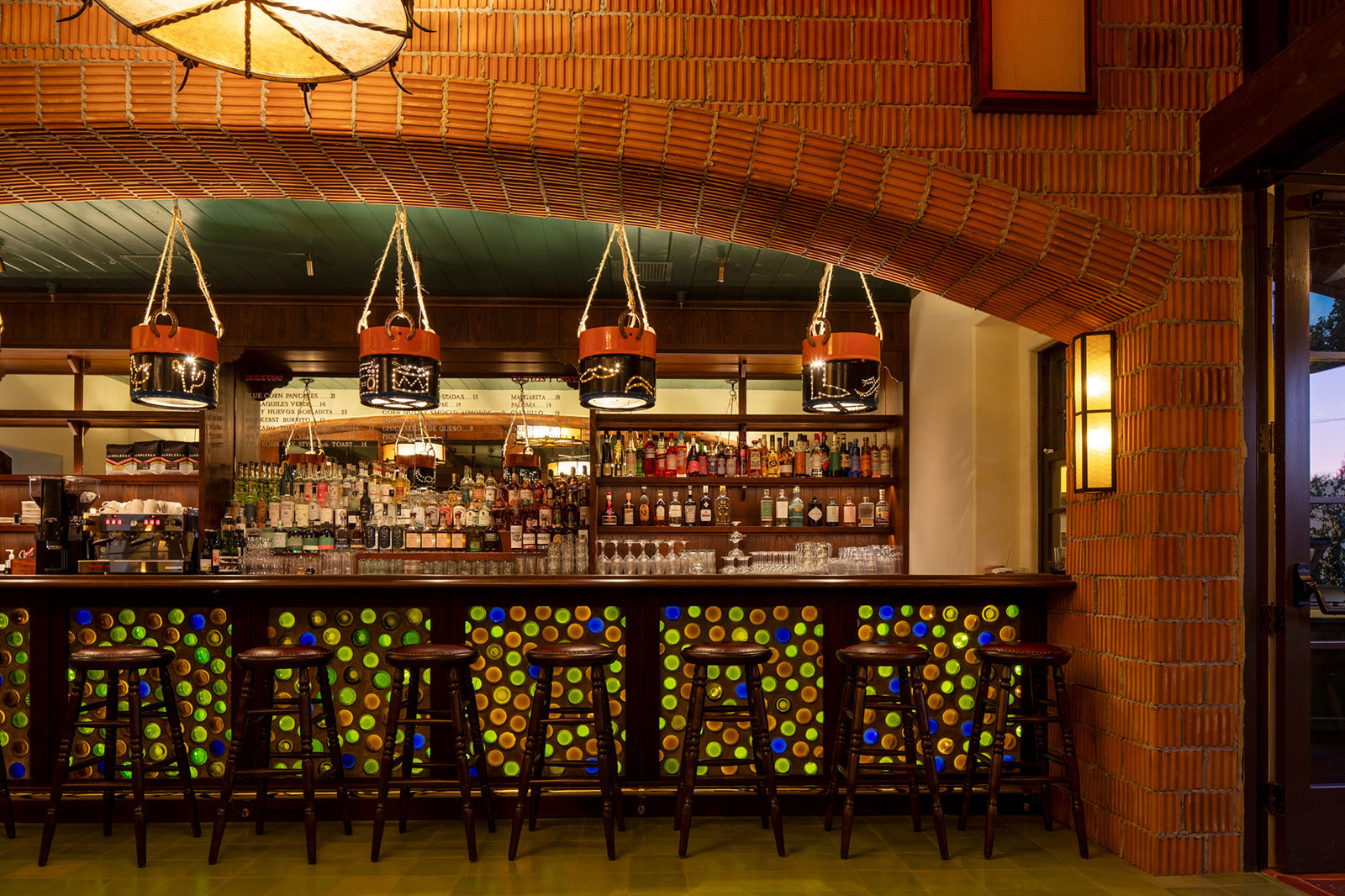 a bar with a row of stools and bottles