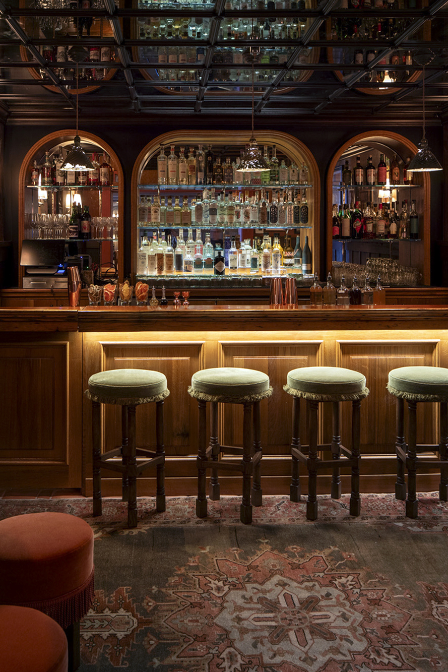 a bar with stools and shelves of liquor