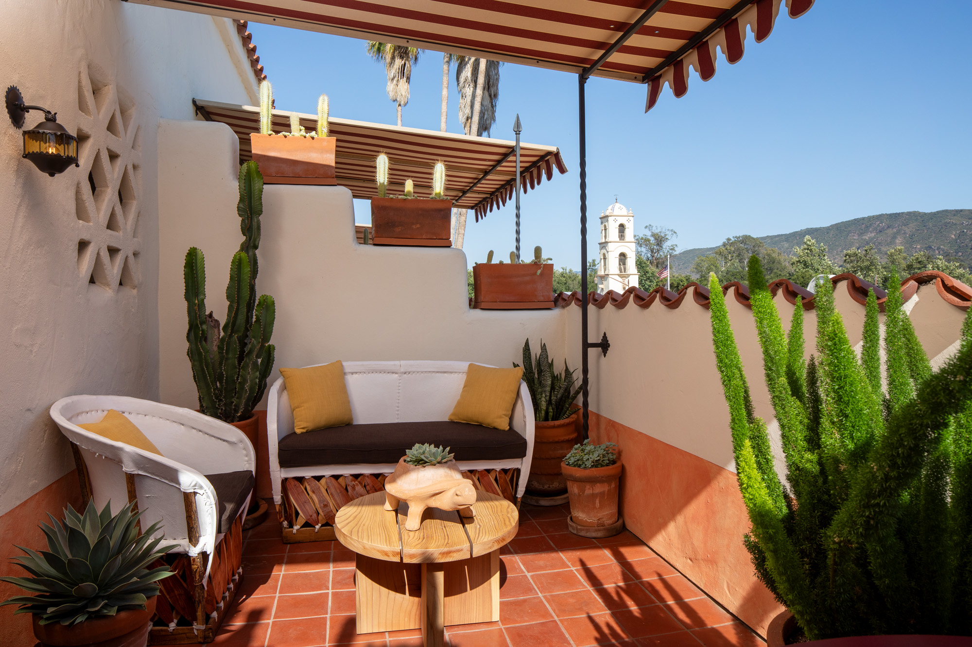 a patio with a couch and a table and cactuses