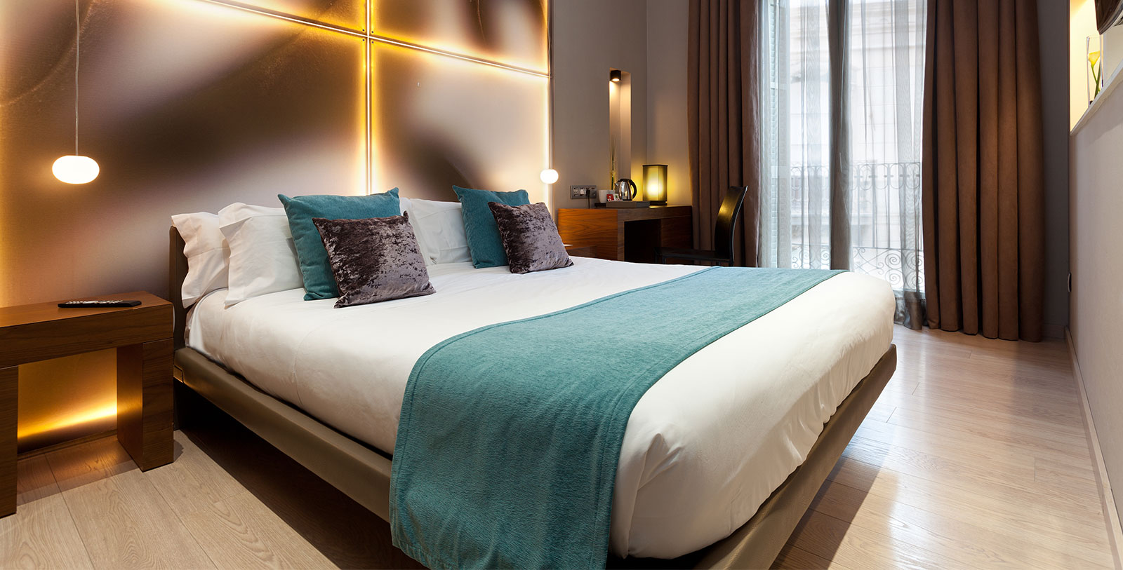 a bed with pillows and a table in front of a window