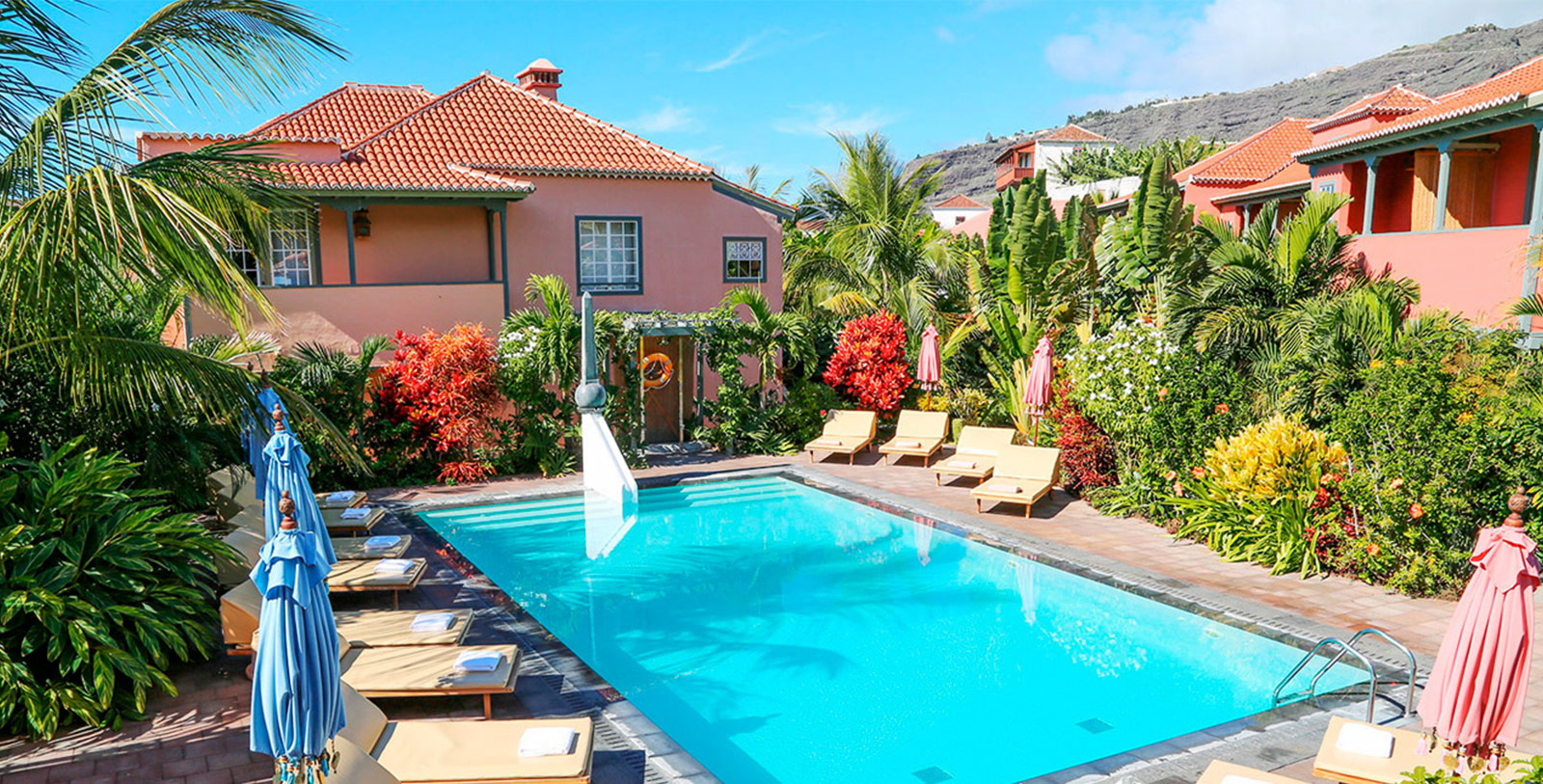 a pool with lounge chairs and a house in the background