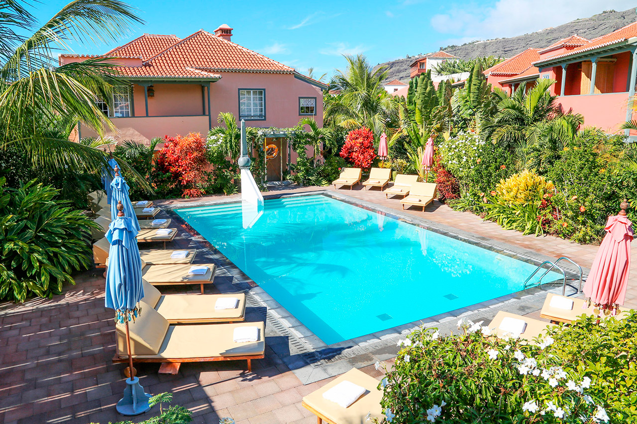 a pool with lounge chairs and umbrellas in a backyard