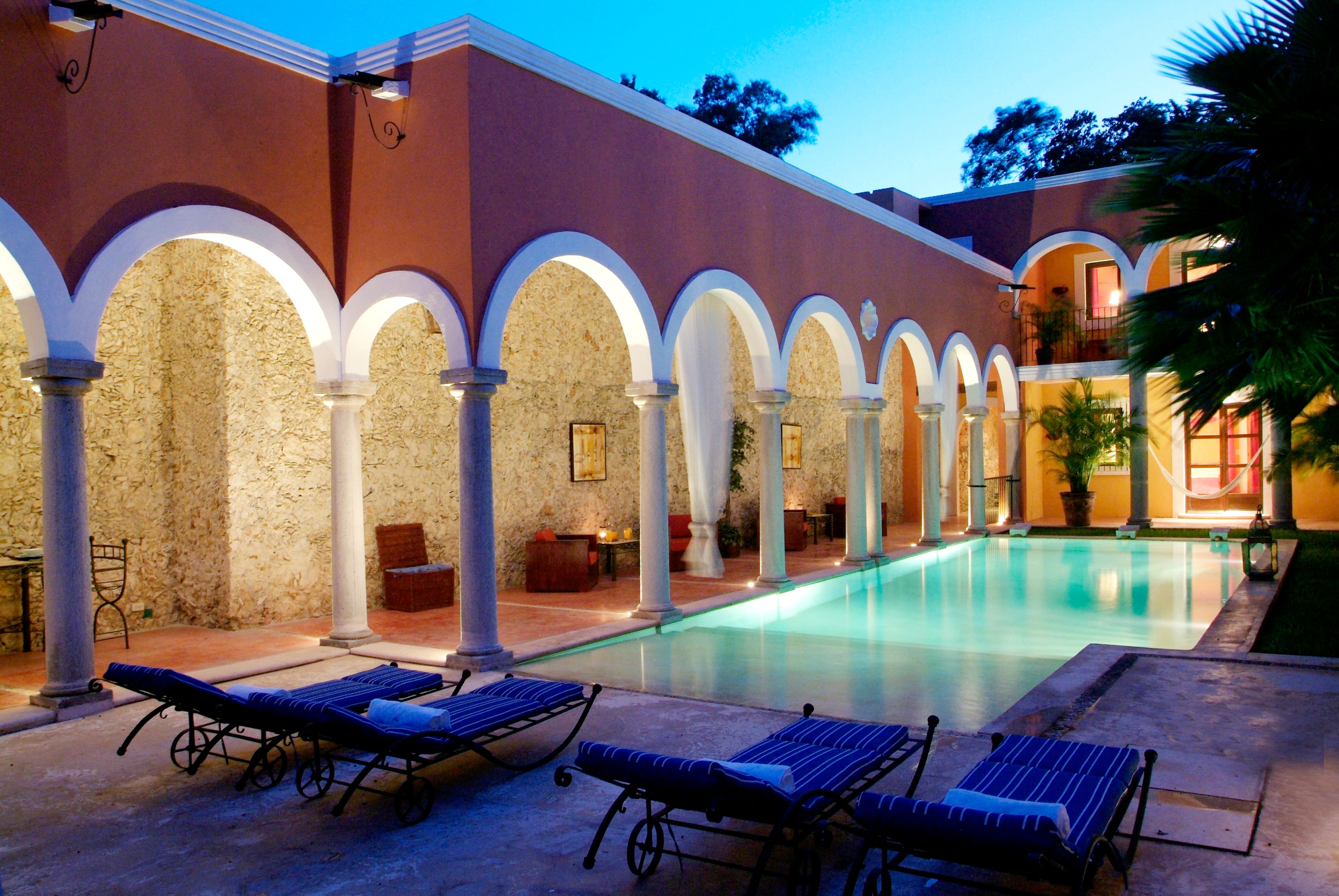 a pool with lounge chairs and a building with columns