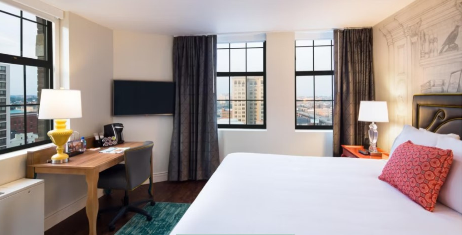 a room with a bed and desk and windows