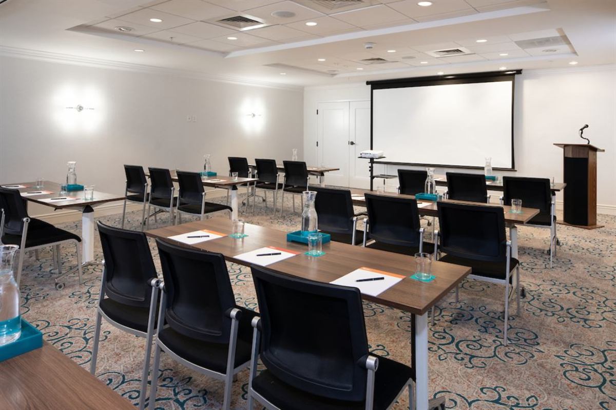 a room with a large screen and tables