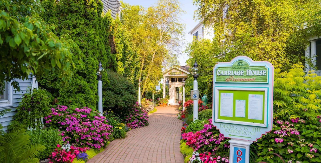 a brick path with flowers and a sign