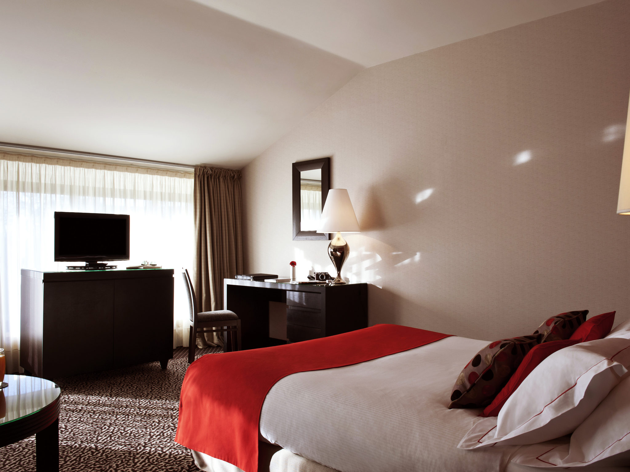 a bedroom with a red blanket and a desk