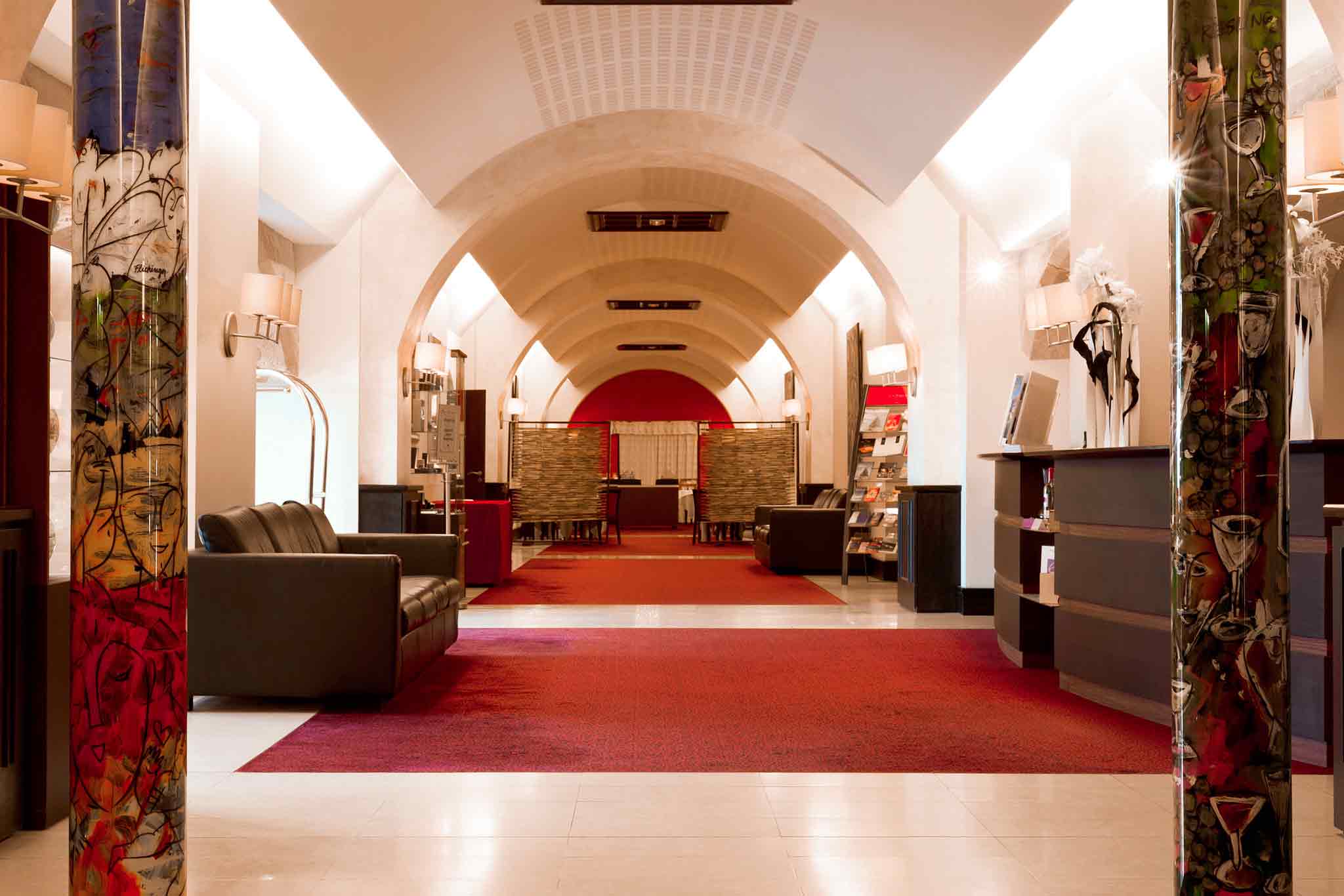 a hallway with a red carpet and couches