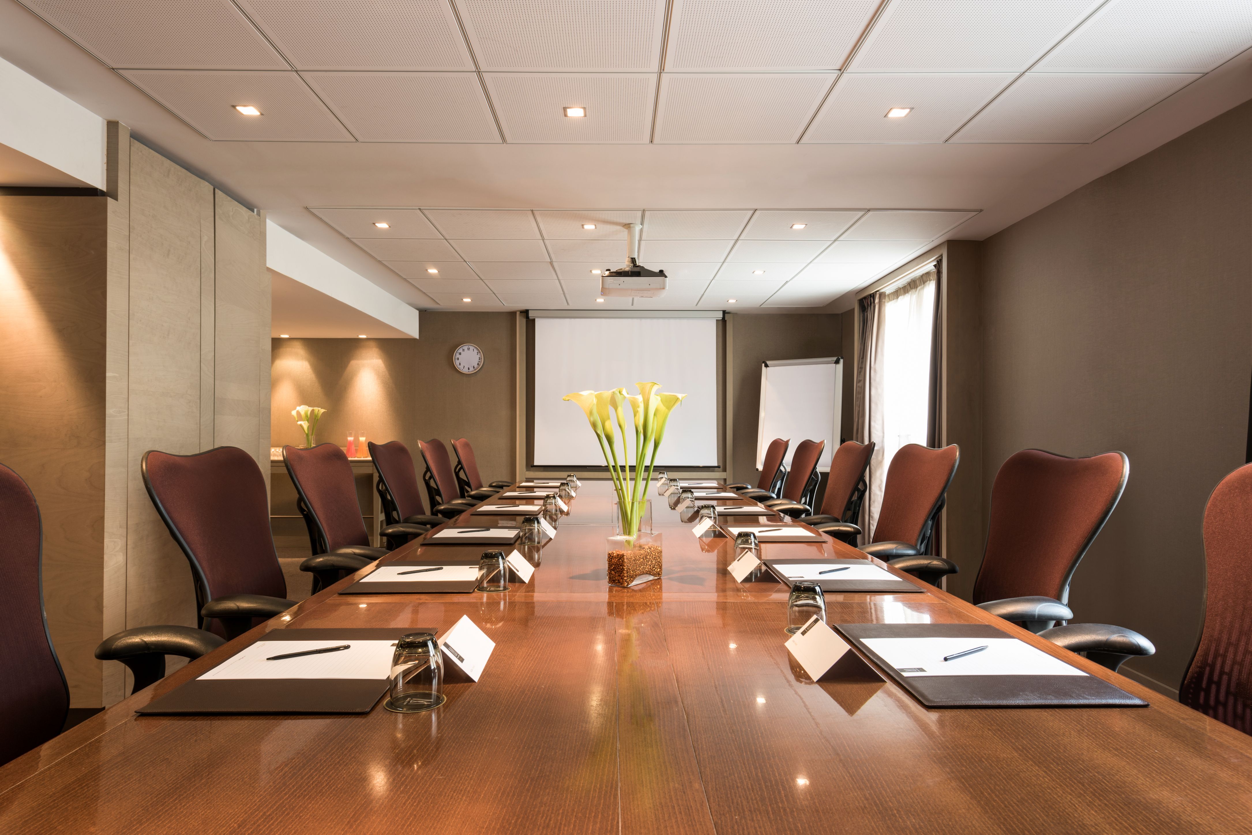 a conference room with chairs and a table with papers and a flower in a vase