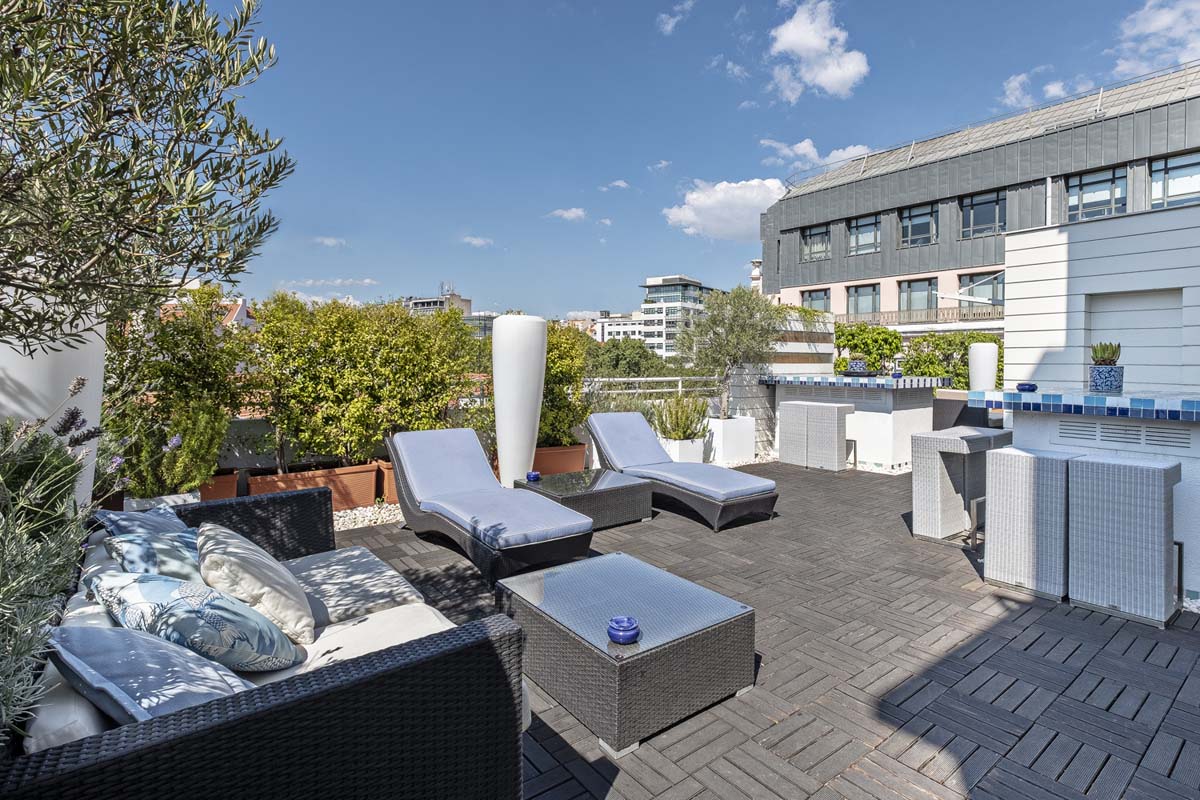 a patio with chairs and tables on a rooftop