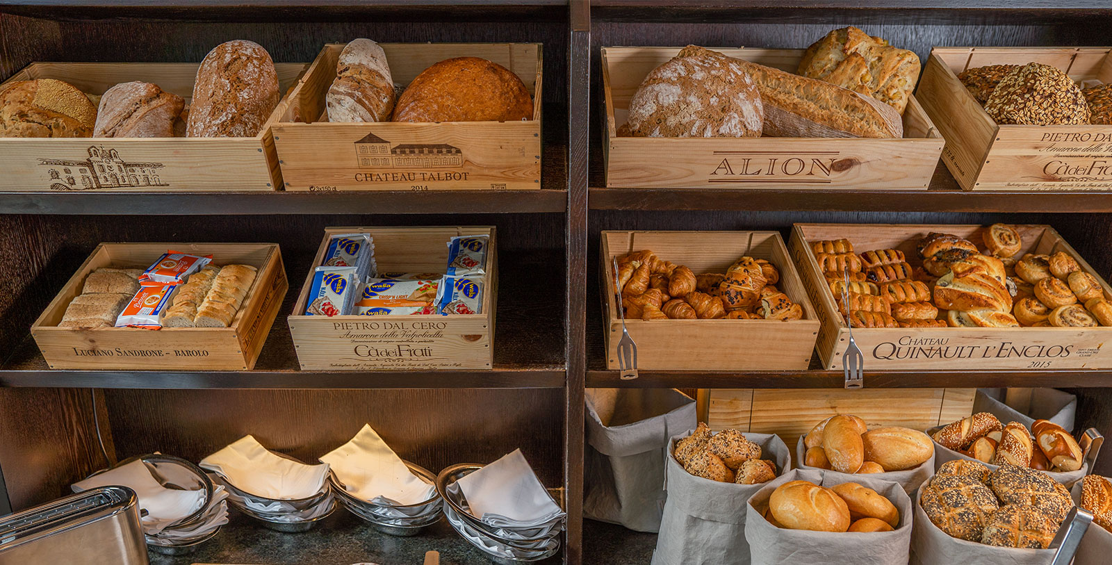 a shelf with different types of bread in wooden boxes