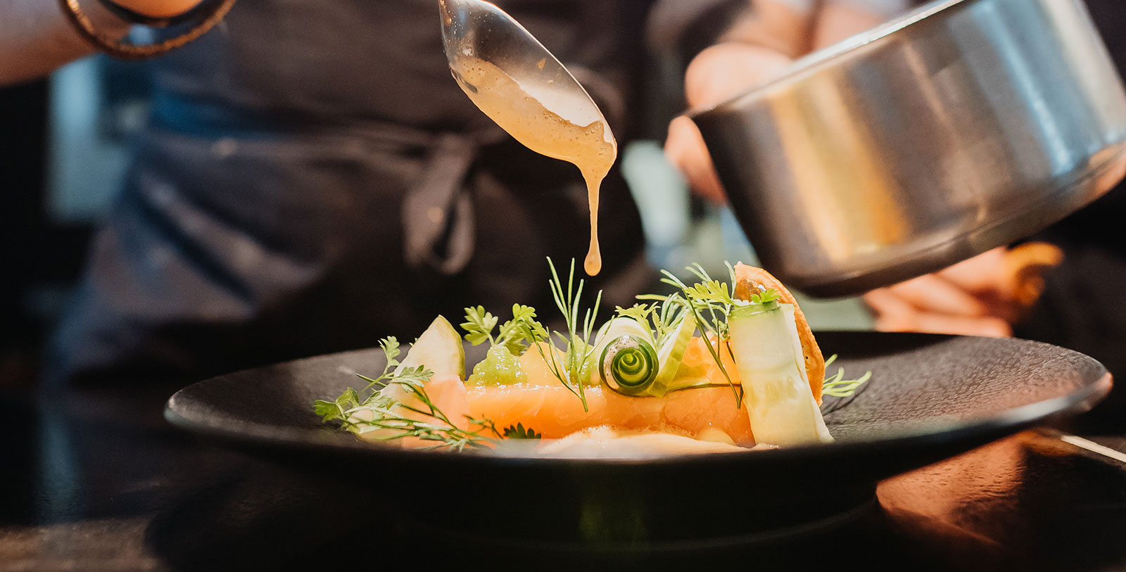 a person pouring sauce over food