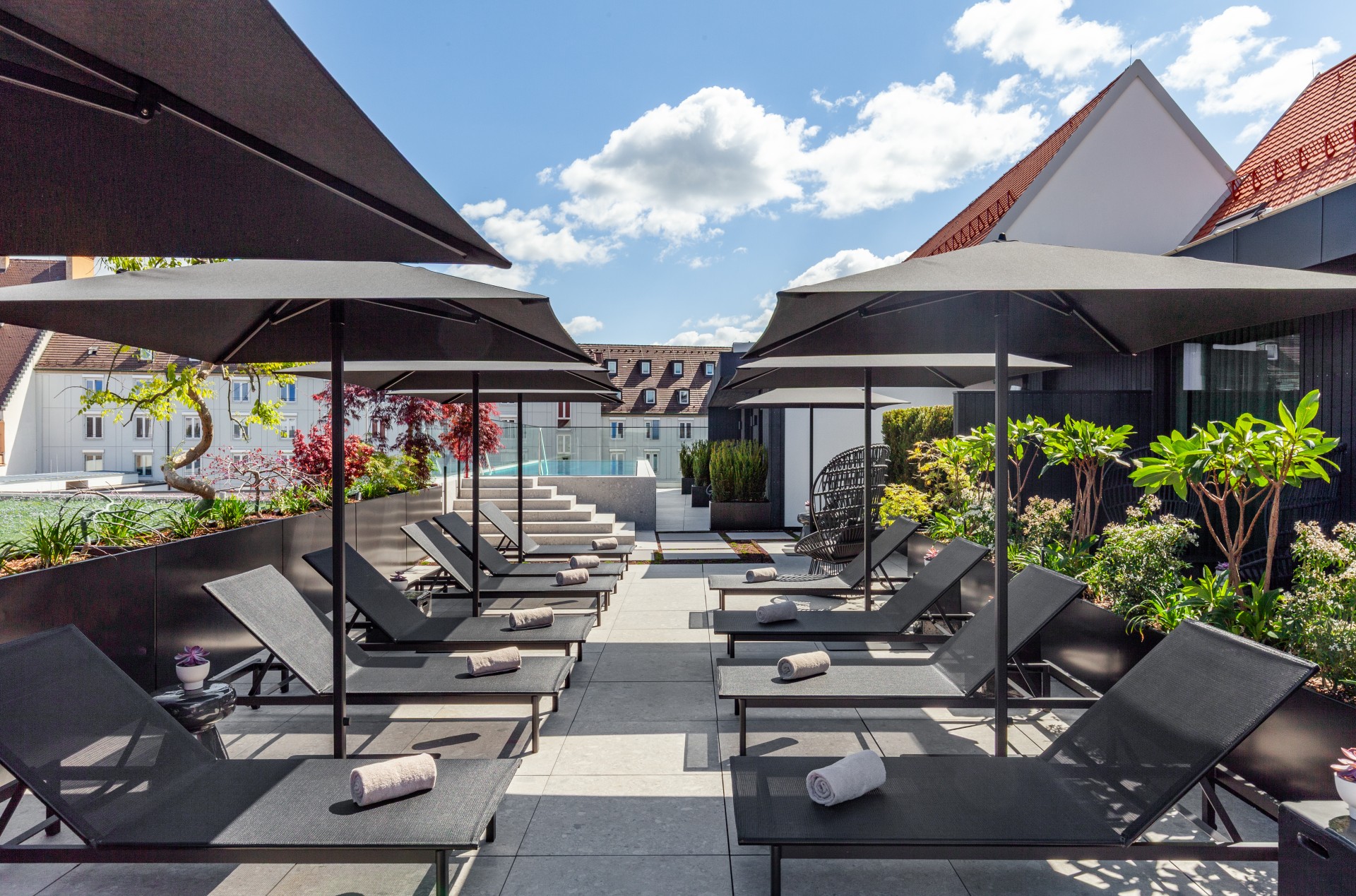 a group of lounge chairs and umbrellas on a patio