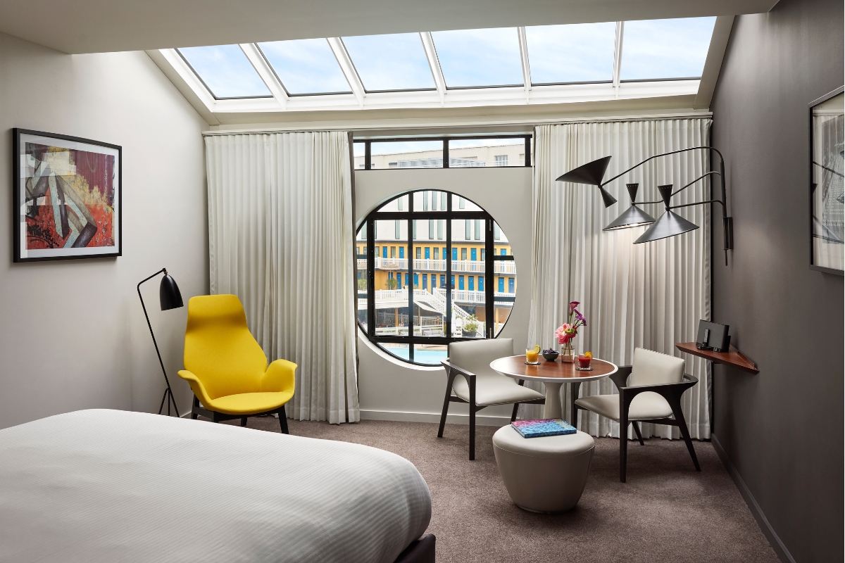 a room with a bed and chairs and a round window