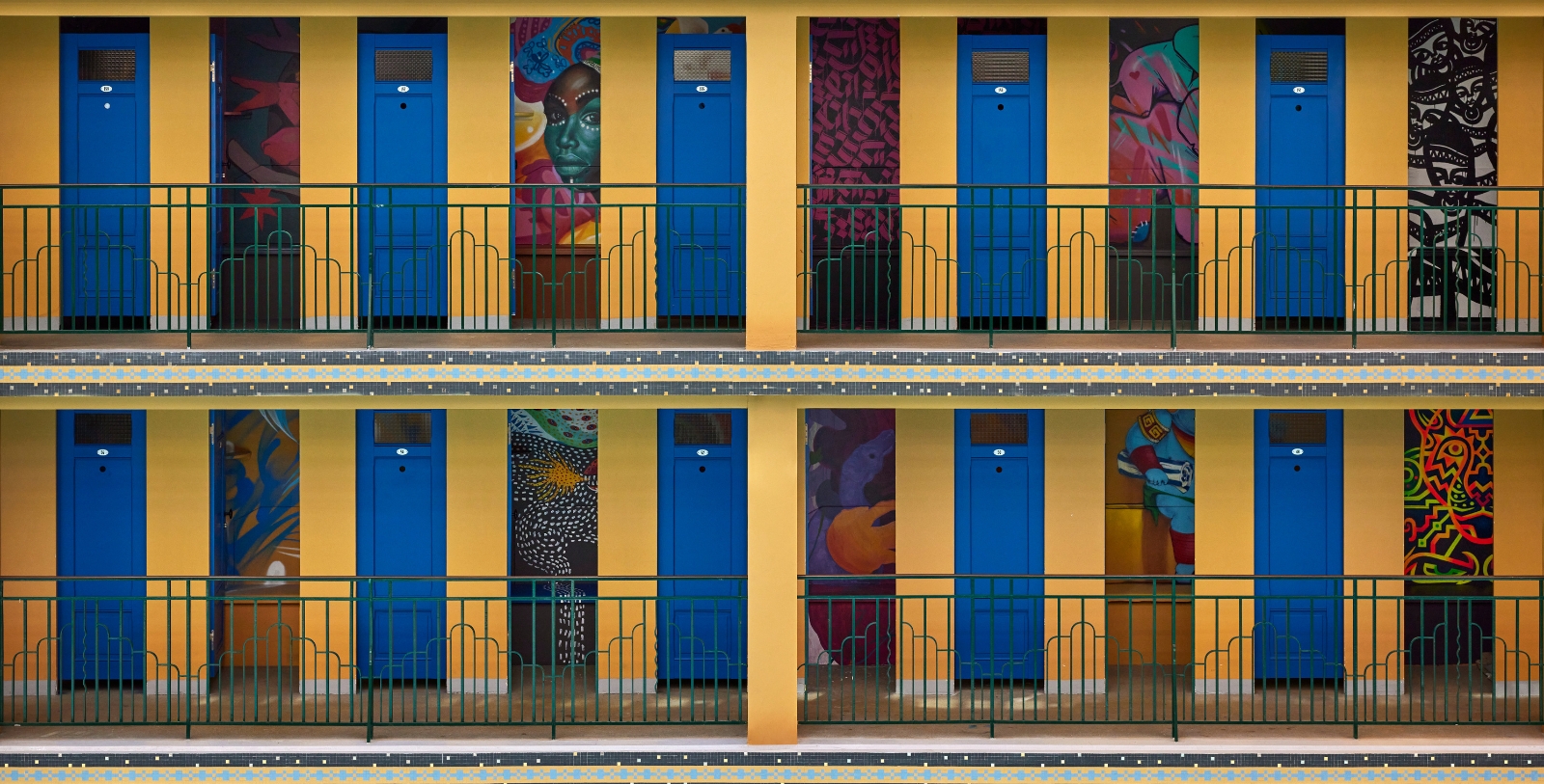 a row of blue doors with art on the wall
