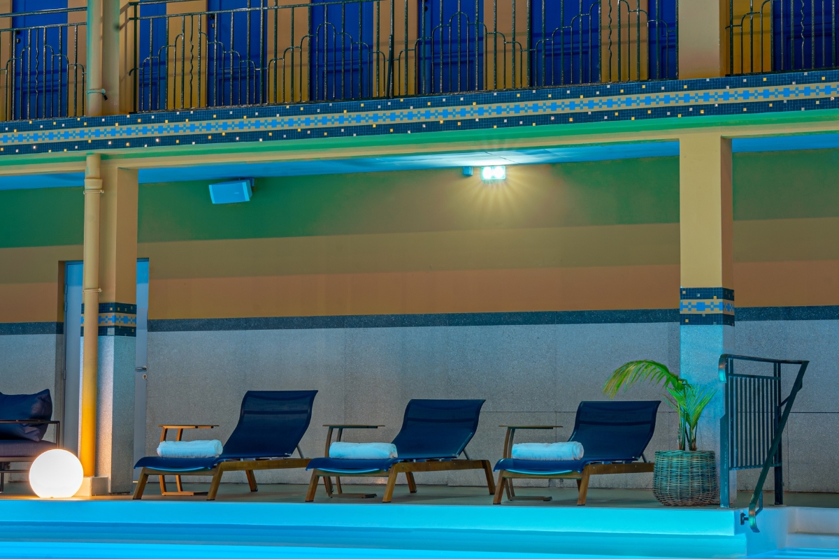 a pool with lounge chairs and a potted plant