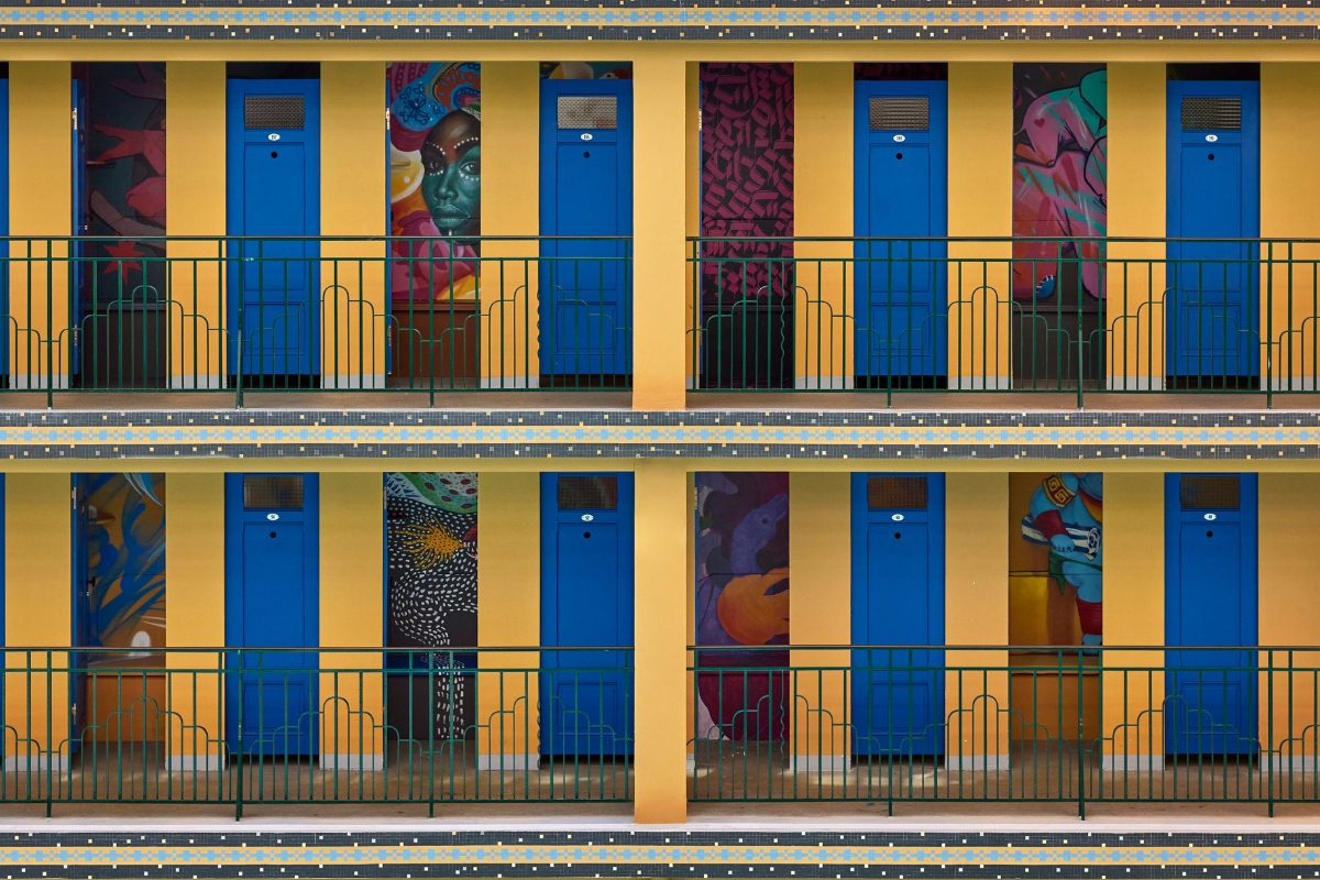a row of blue doors with art on the wall