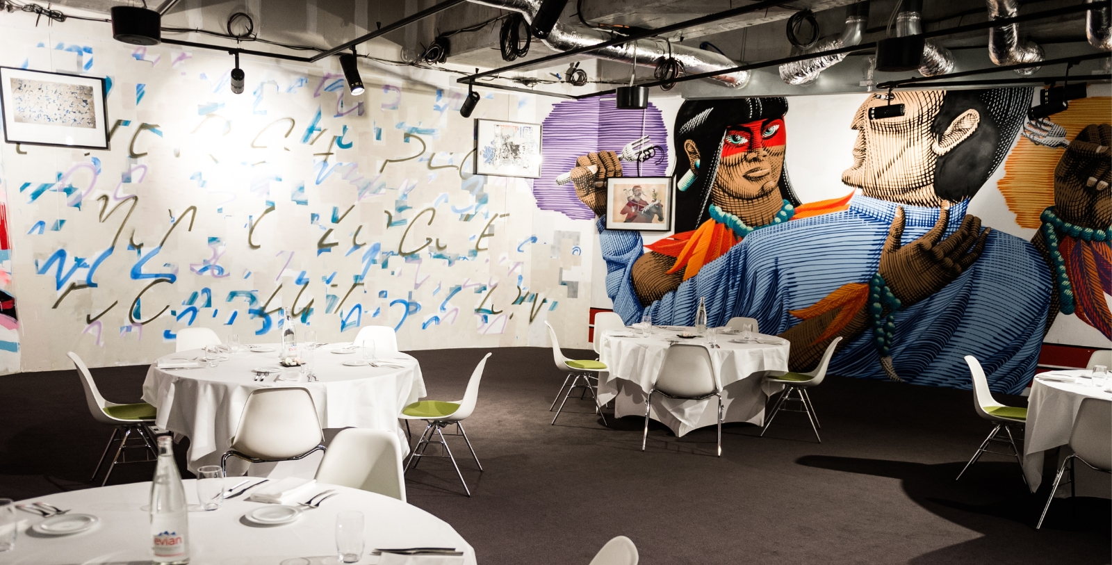 a room with tables and chairs and a mural of a woman holding a microphone