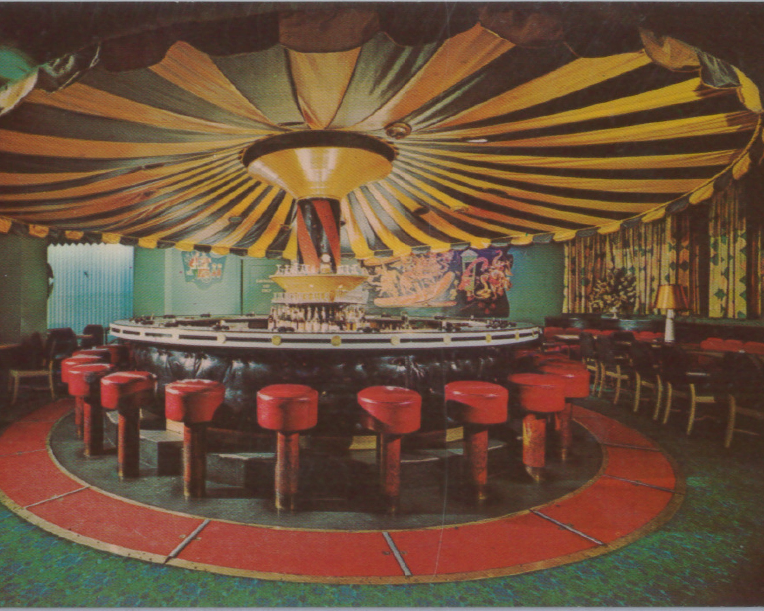 a round table with red stools and a yellow and black striped ceiling