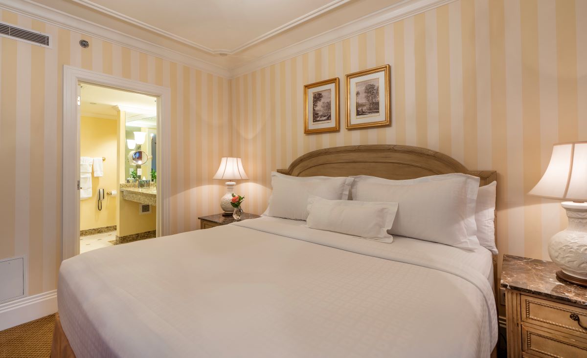 a bed with white sheets and a lamp in a room