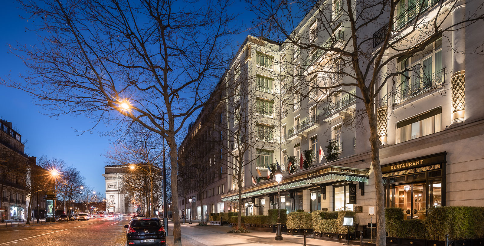 a building with lights on and trees on the side