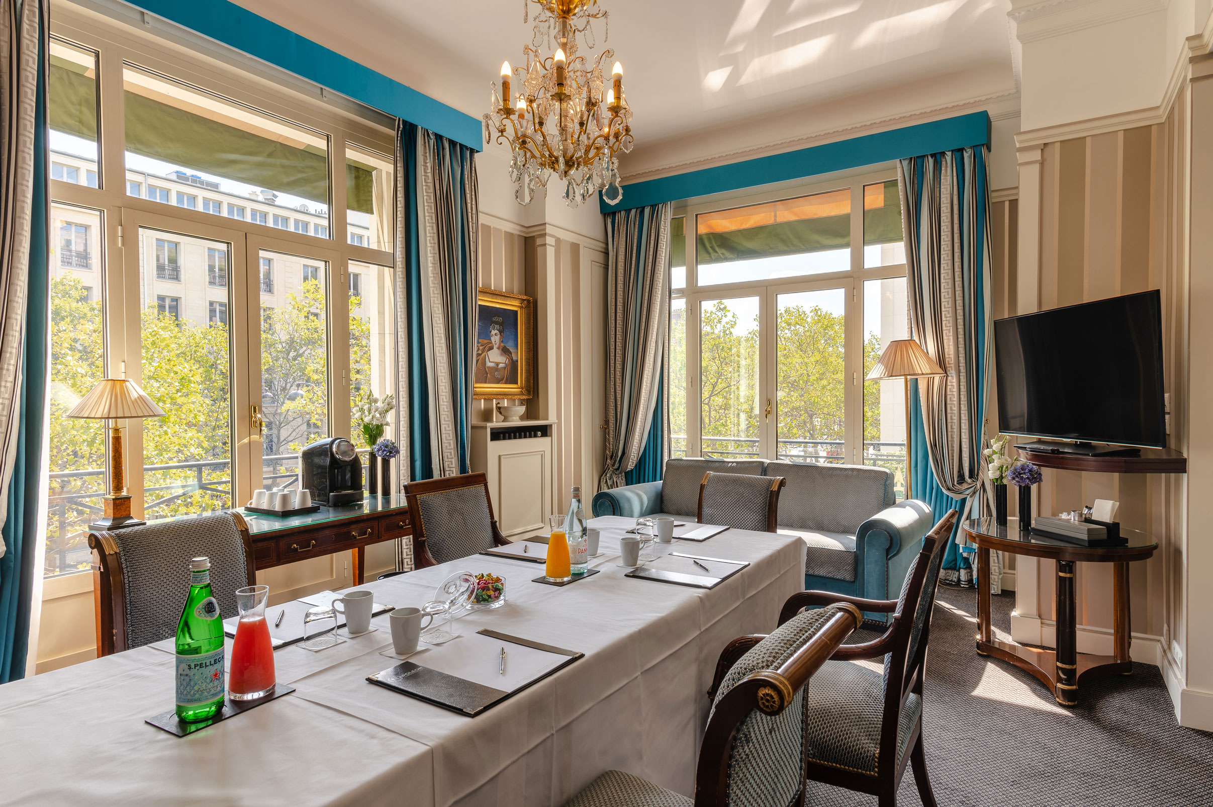 a room with a chandelier and a table with chairs and a couch