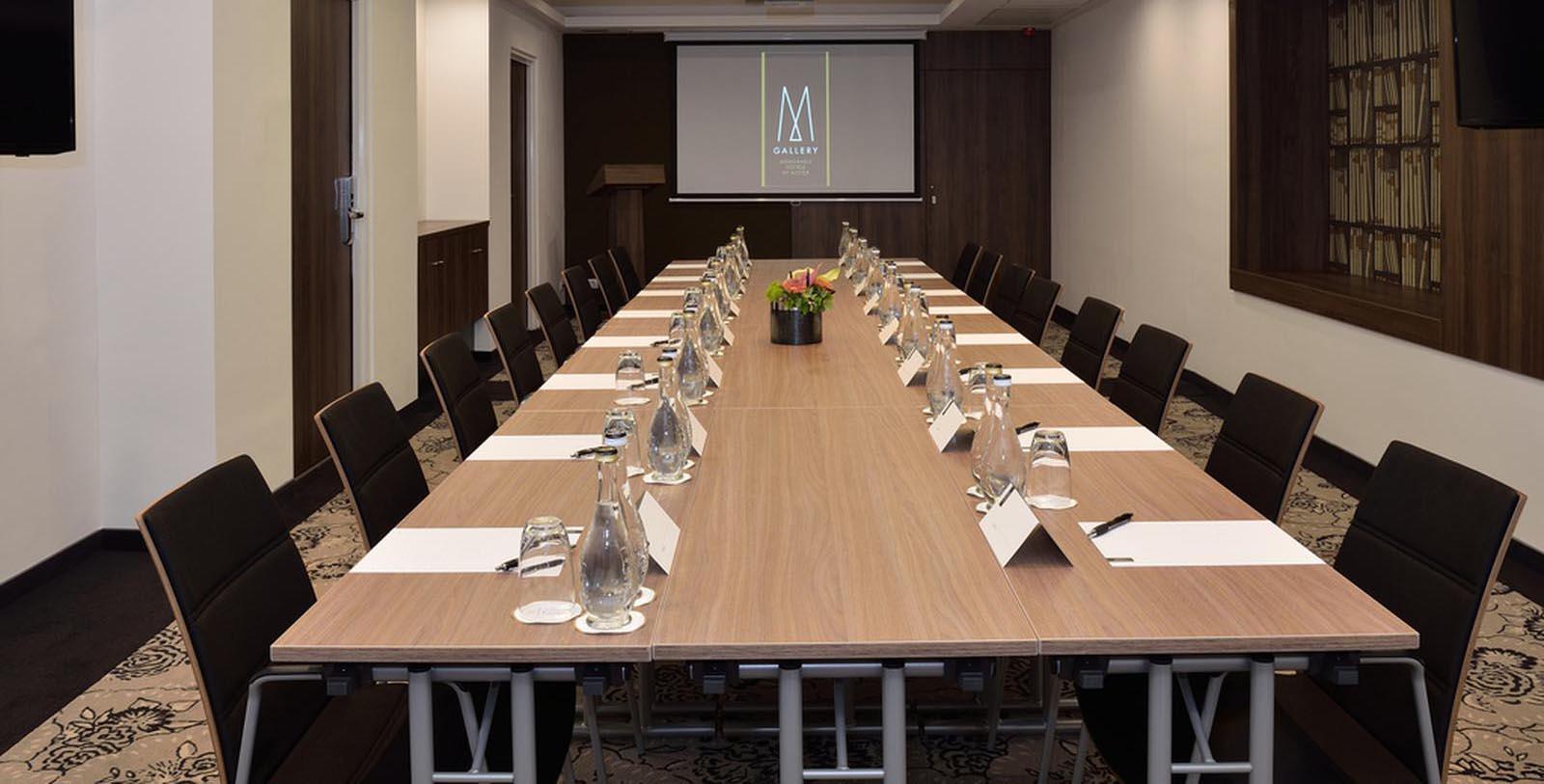 a long conference table with chairs and a projector screen