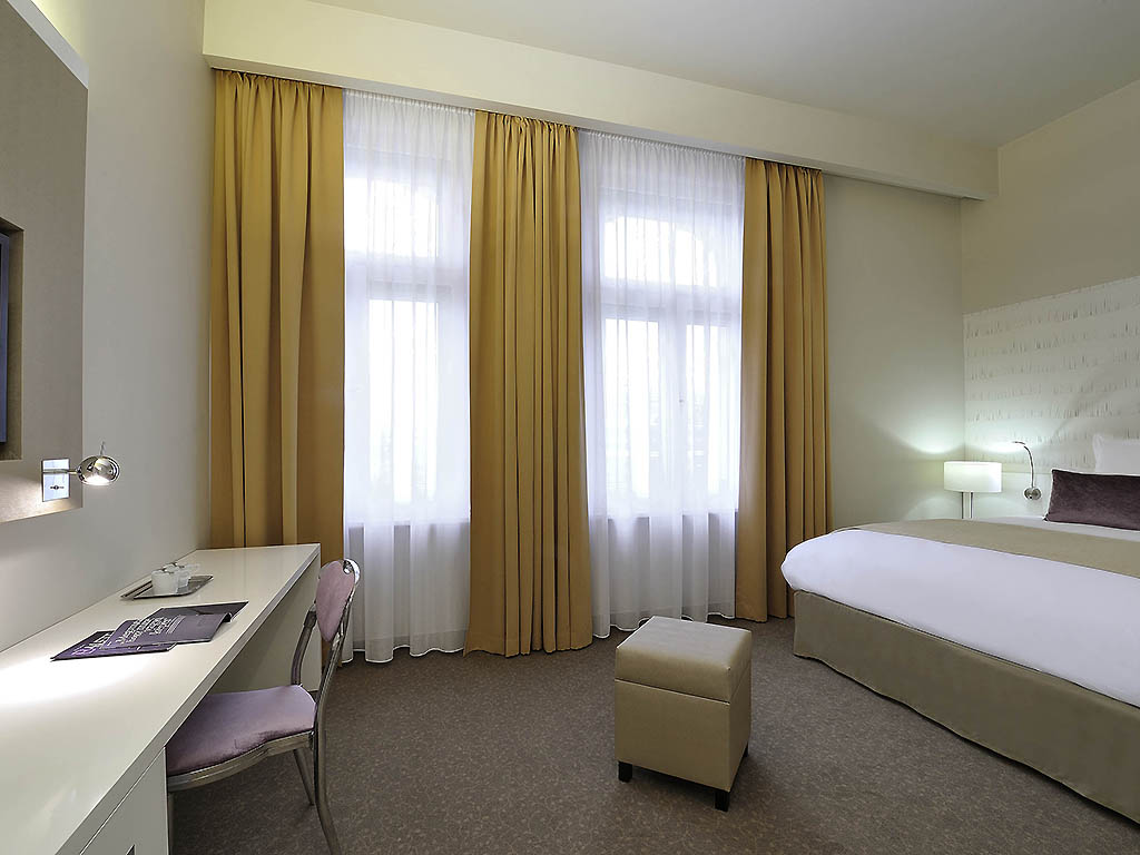 a room with a bed and a desk and curtains