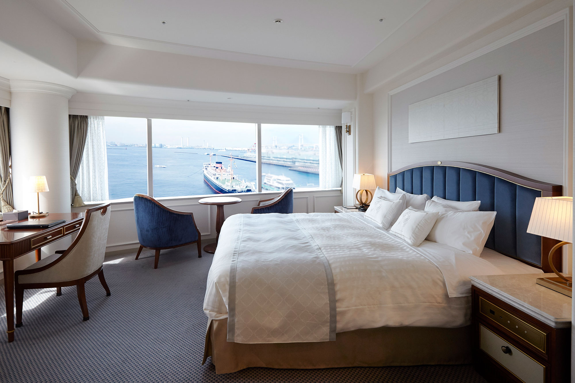 a room with a bed and chairs and a large window