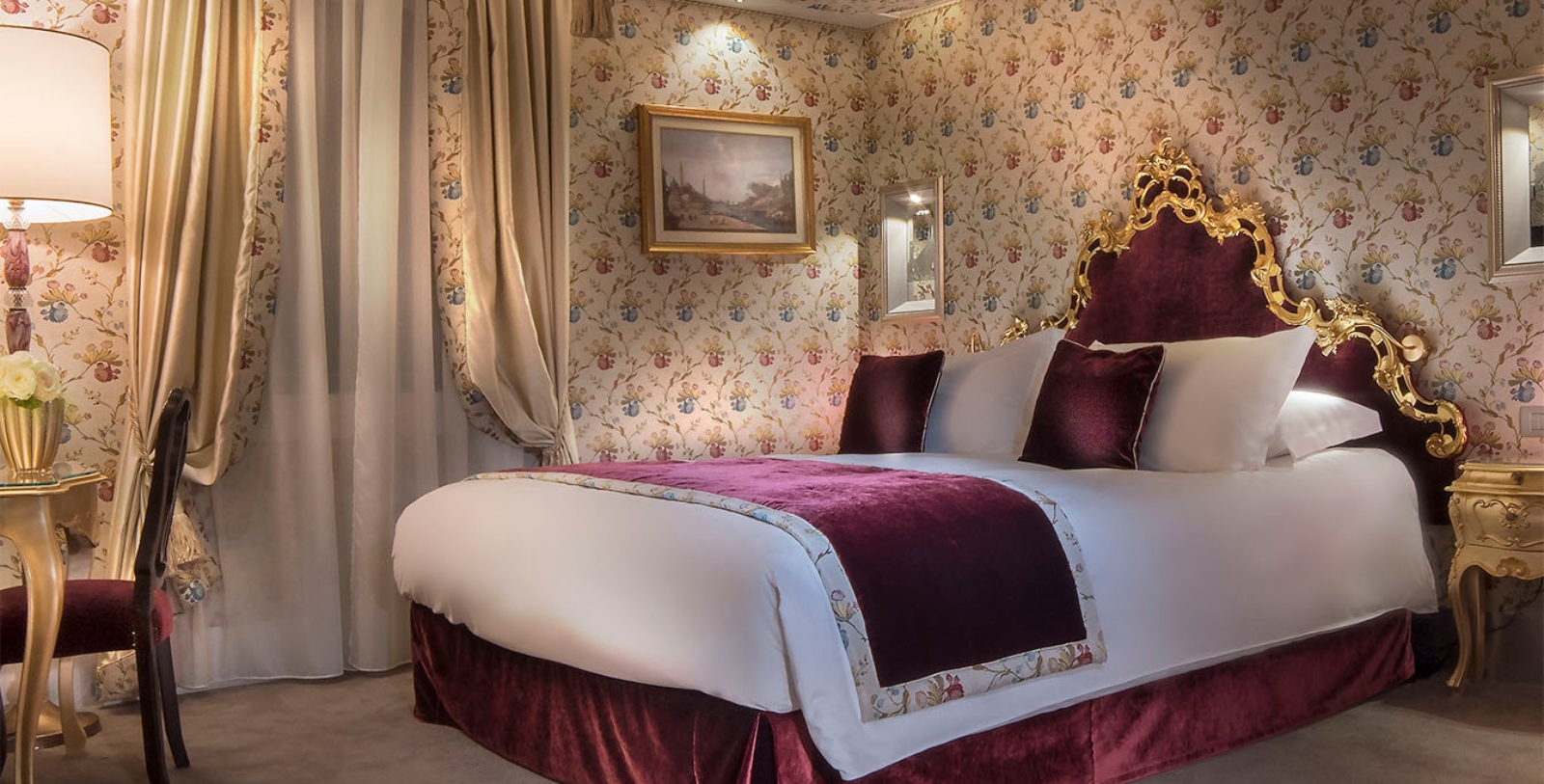a bed with a red blanket and a picture on the wall