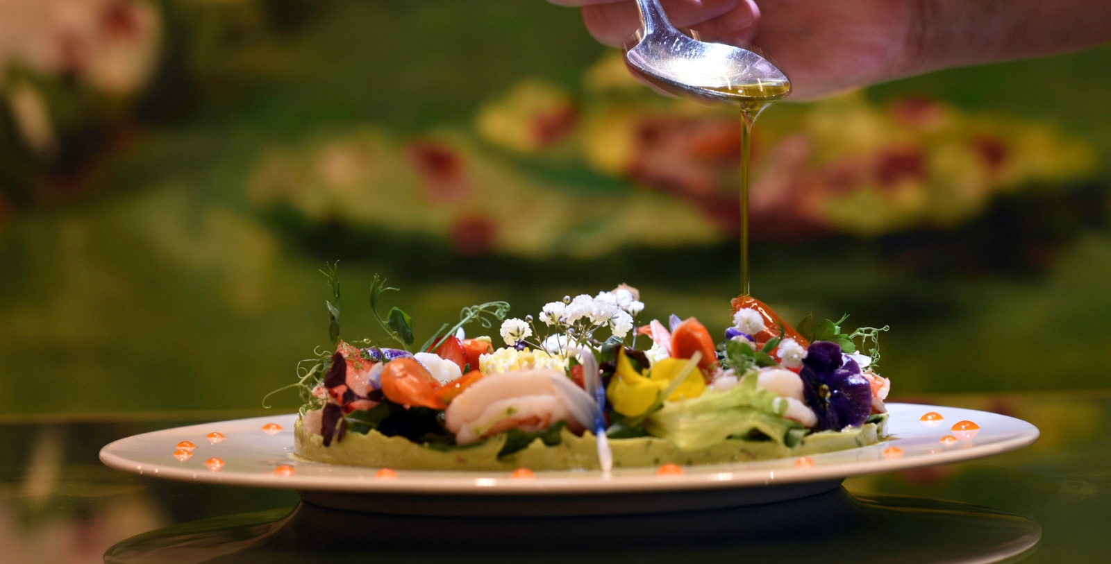 a person pouring oil onto a plate of food