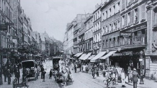 a street with people and horse carriages