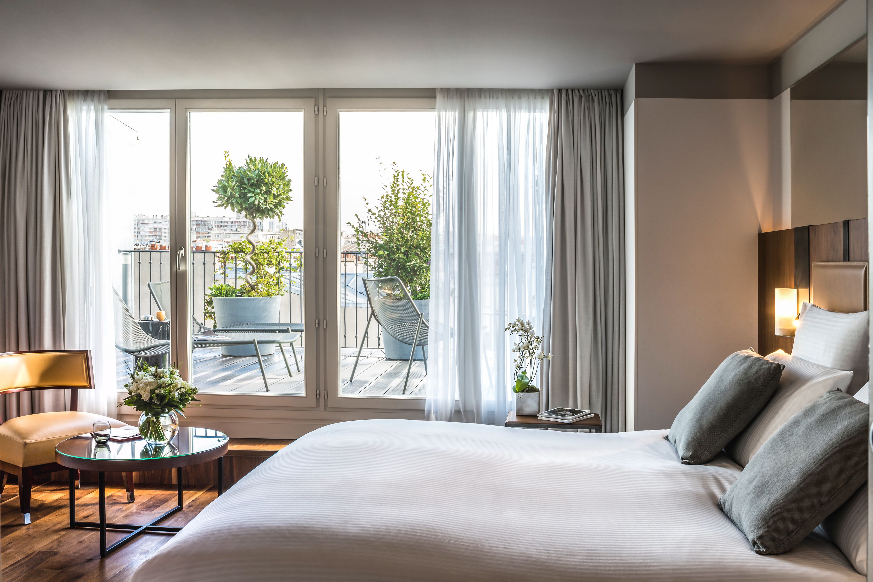 a bedroom with a bed and a table with plants outside