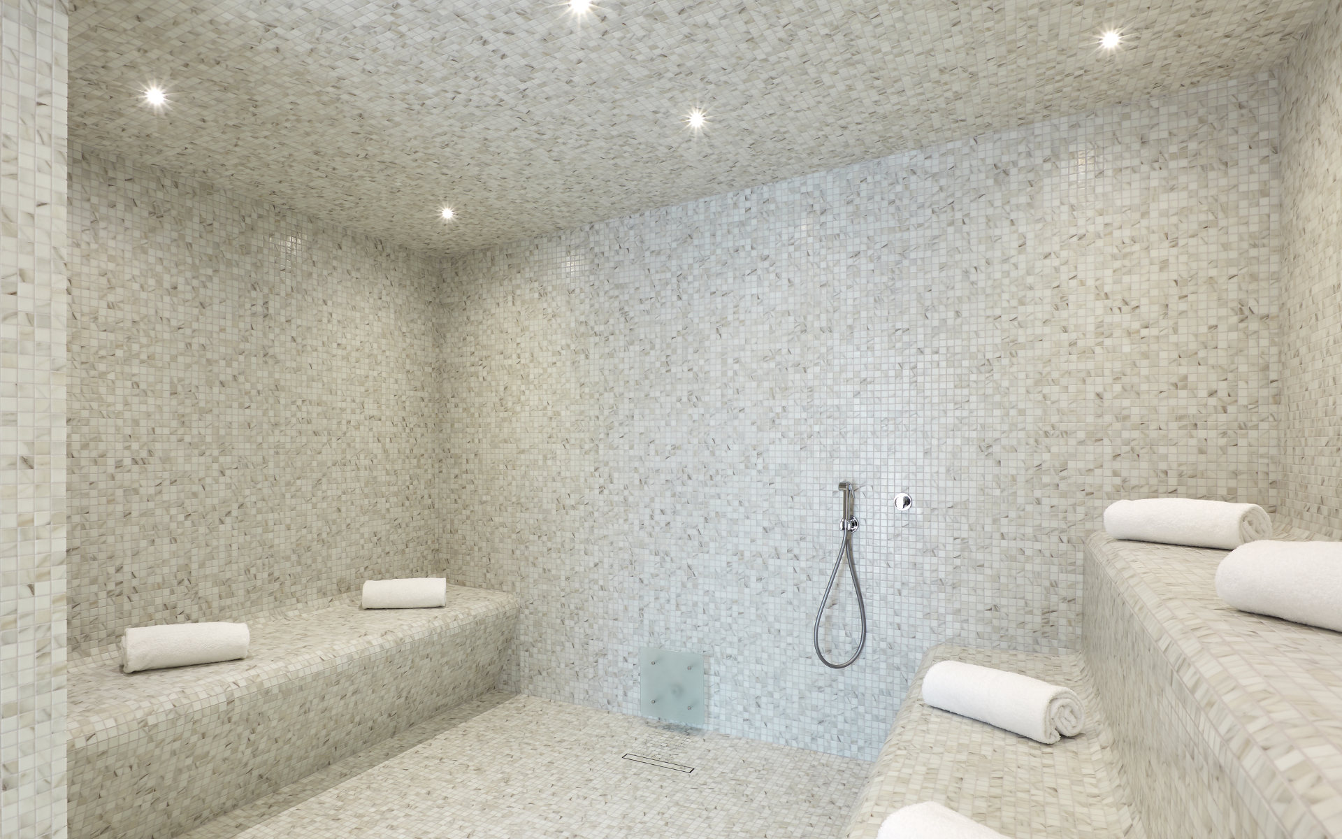 a white tiled shower with a bench and a shower head