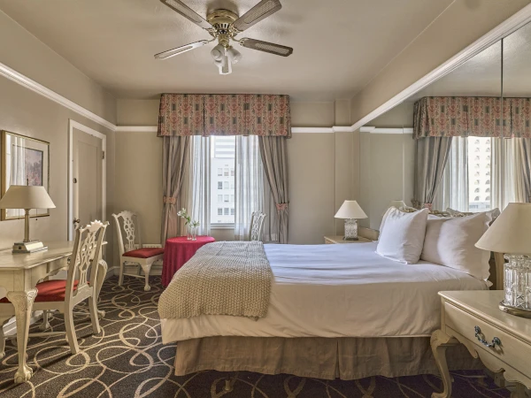 a room with a bed and chairs and a ceiling fan