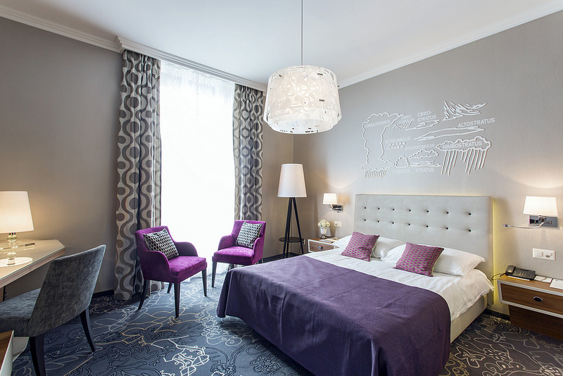 a bedroom with purple furniture and a lamp
